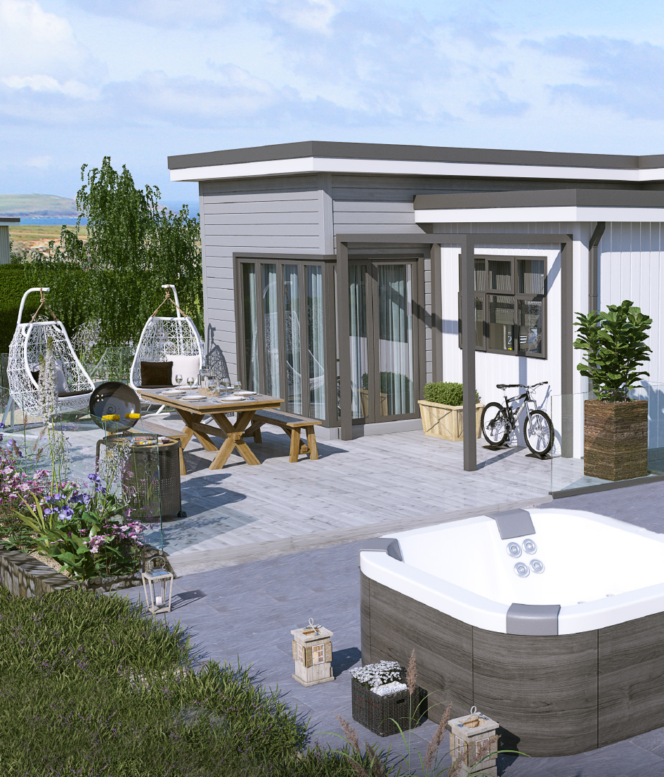 A modern residential park home outdoor patio with seating, a hot tub, bicycles, and landscaping under a partly cloudy sky.