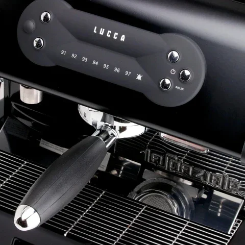Close-up of a LUCCA espresso machine with control buttons and a temperature gauge, part of the espresso brewing area.