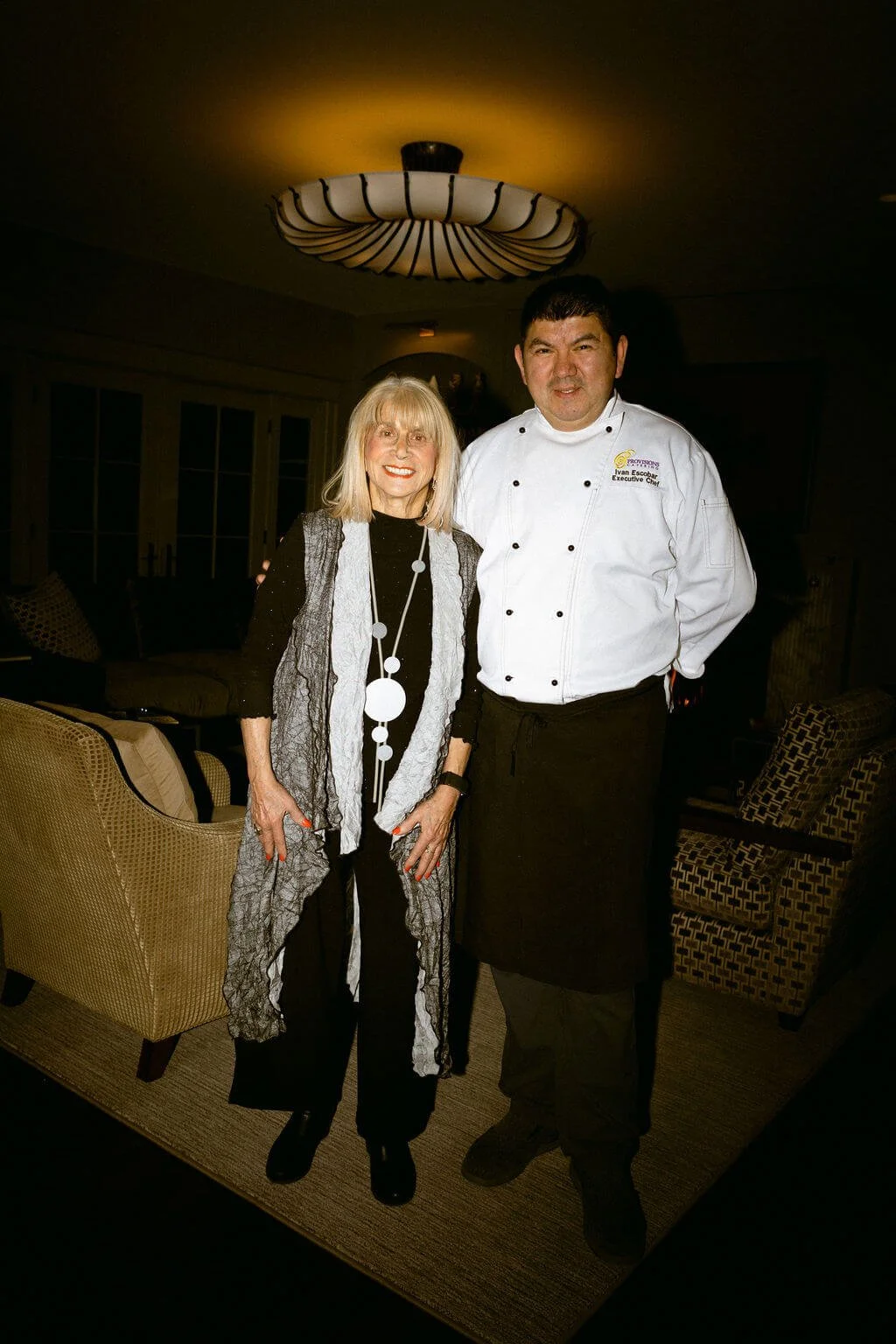 Provisions Catering founder Bunny Dwin and chef Ivan Escobar in a cozy, dimly lit living room preparing for an event.