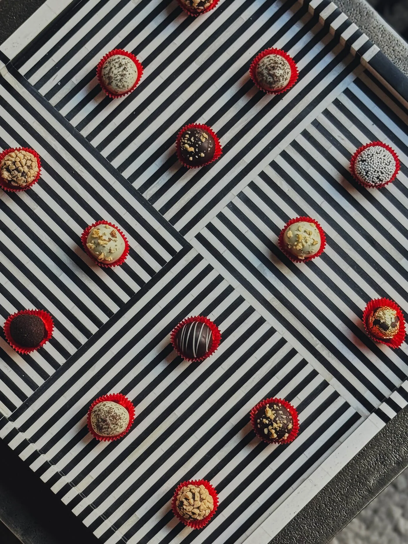 Various decorated chocolates arranged on black and white striped paper.
