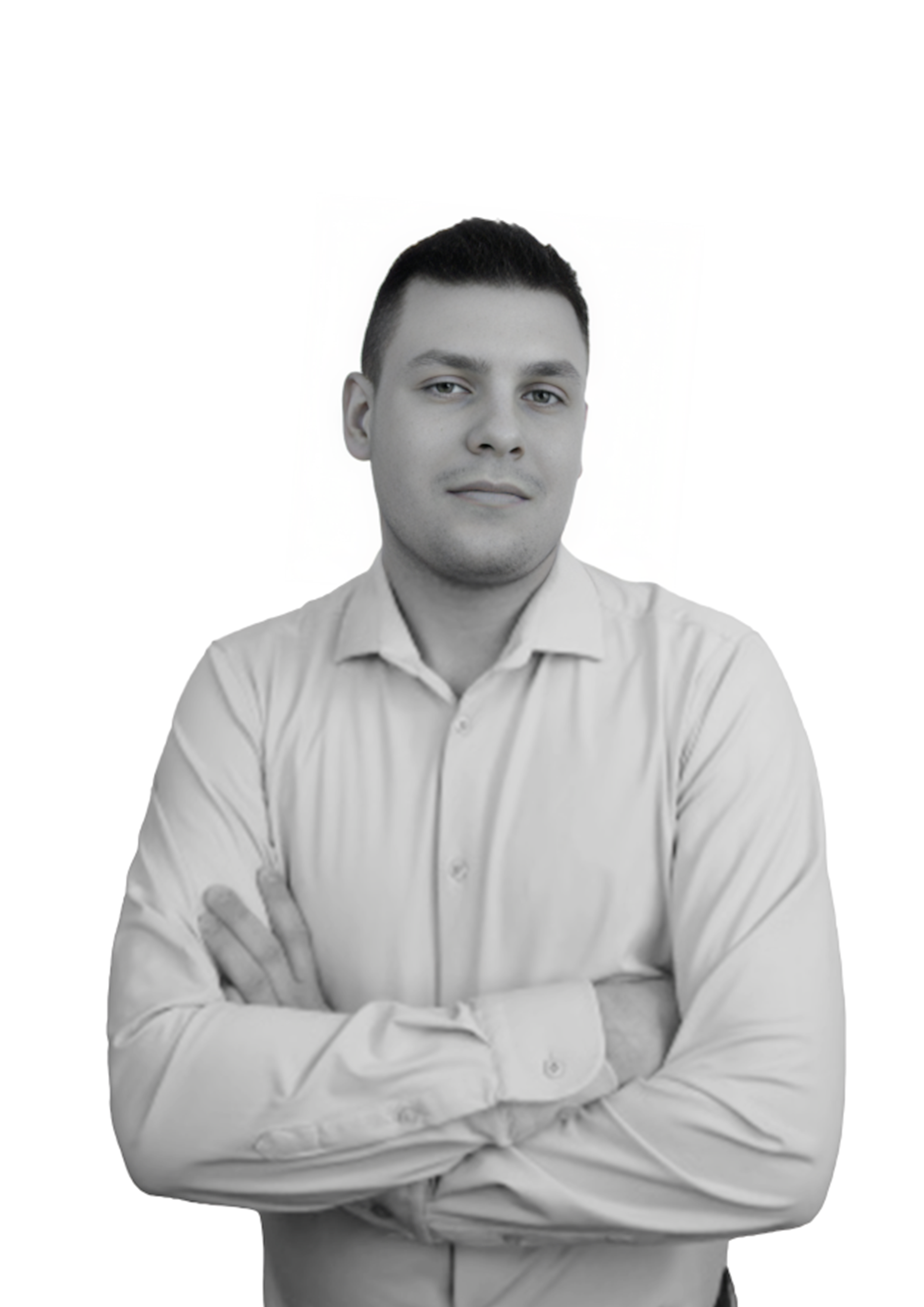A young man with short dark hair and light skin, wearing a light-colored dress shirt with the sleeves rolled up, standing with arms crossed against a plain white background.