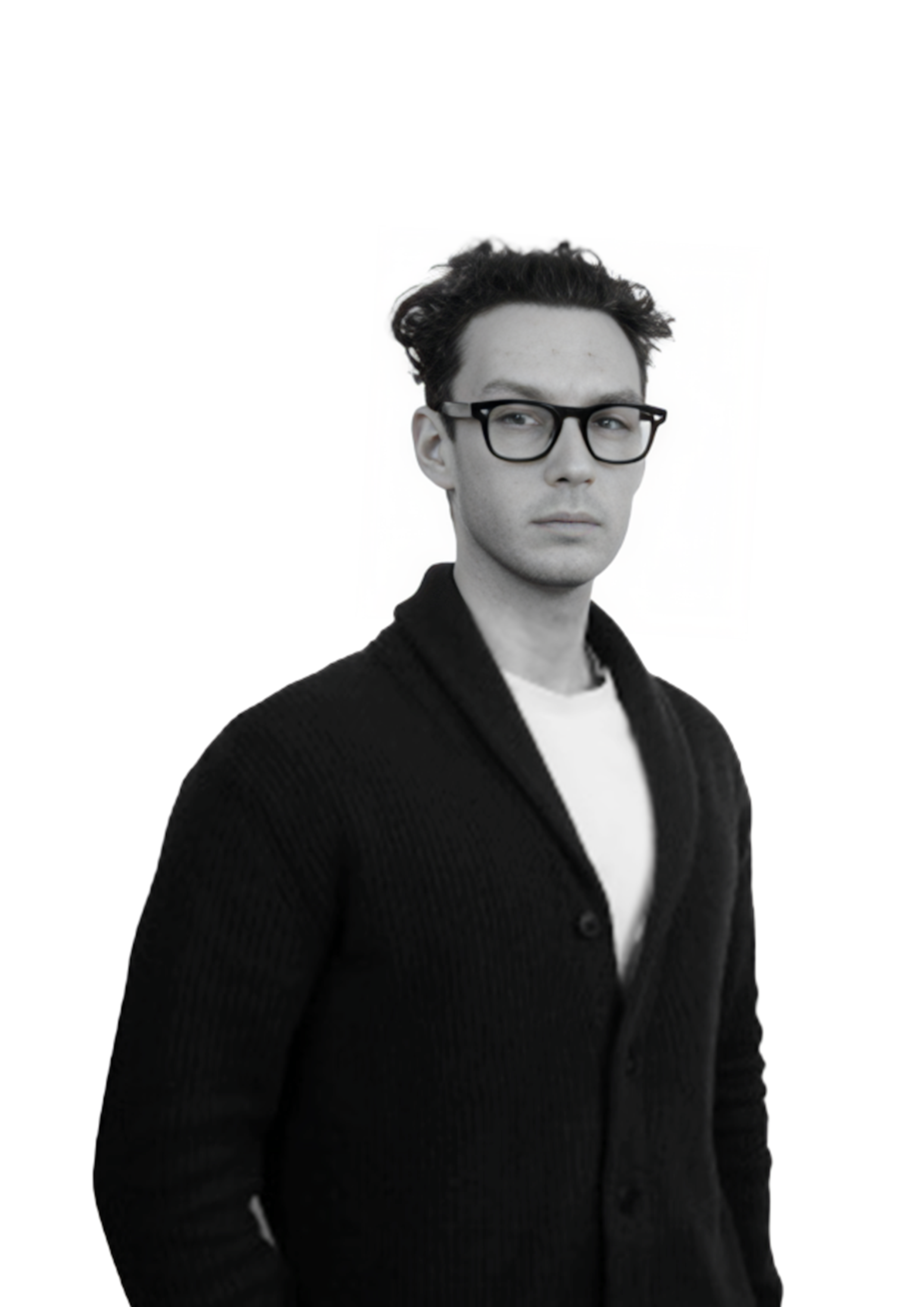 Black and white portrait of a young man with glasses, wearing a dark cardigan over a white shirt, looking serious and slightly to the side, against a white background.