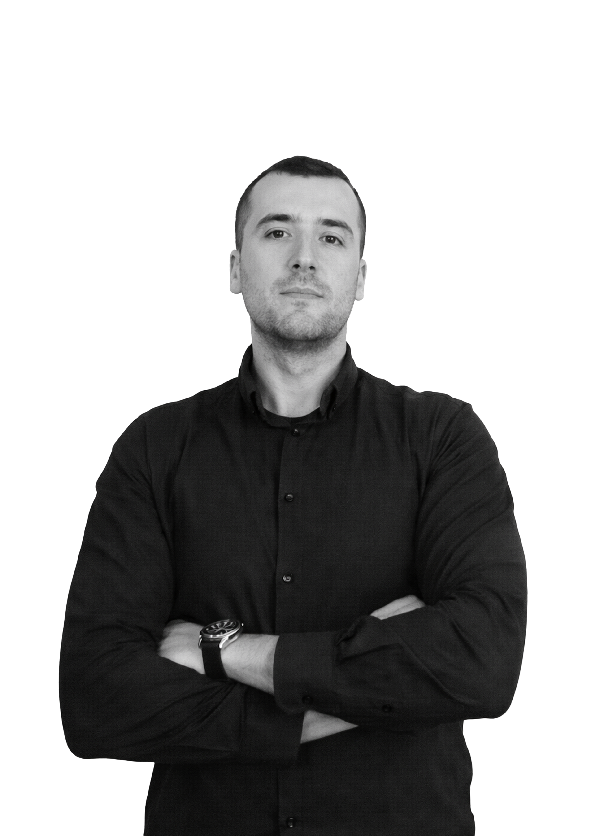 A young man with short hair, wearing a black button-up shirt and a watch, standing with arms crossed against a plain white background.
