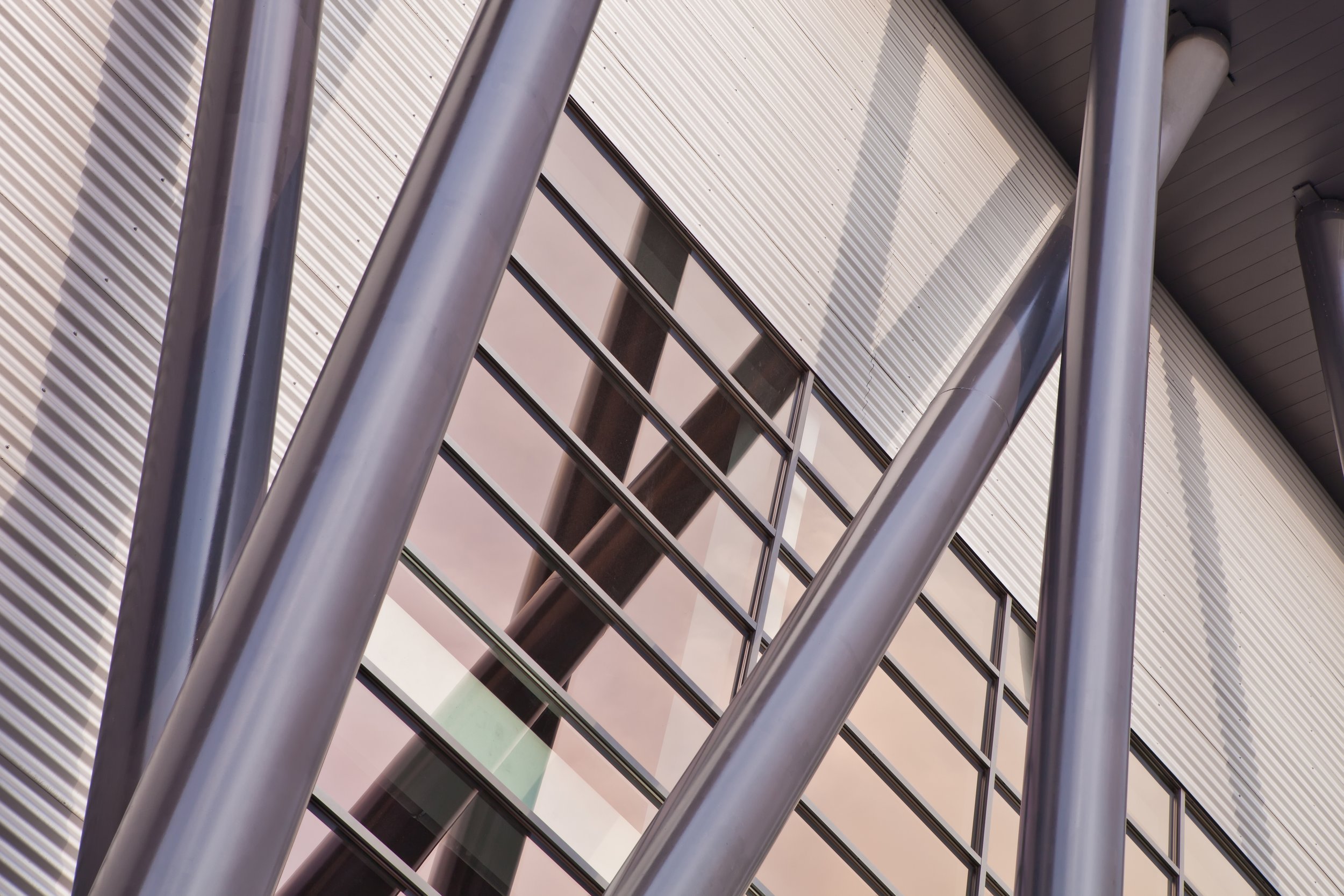 Close-up view of a modern building's exterior with steel beams, glass windows, and ribbed metal siding.