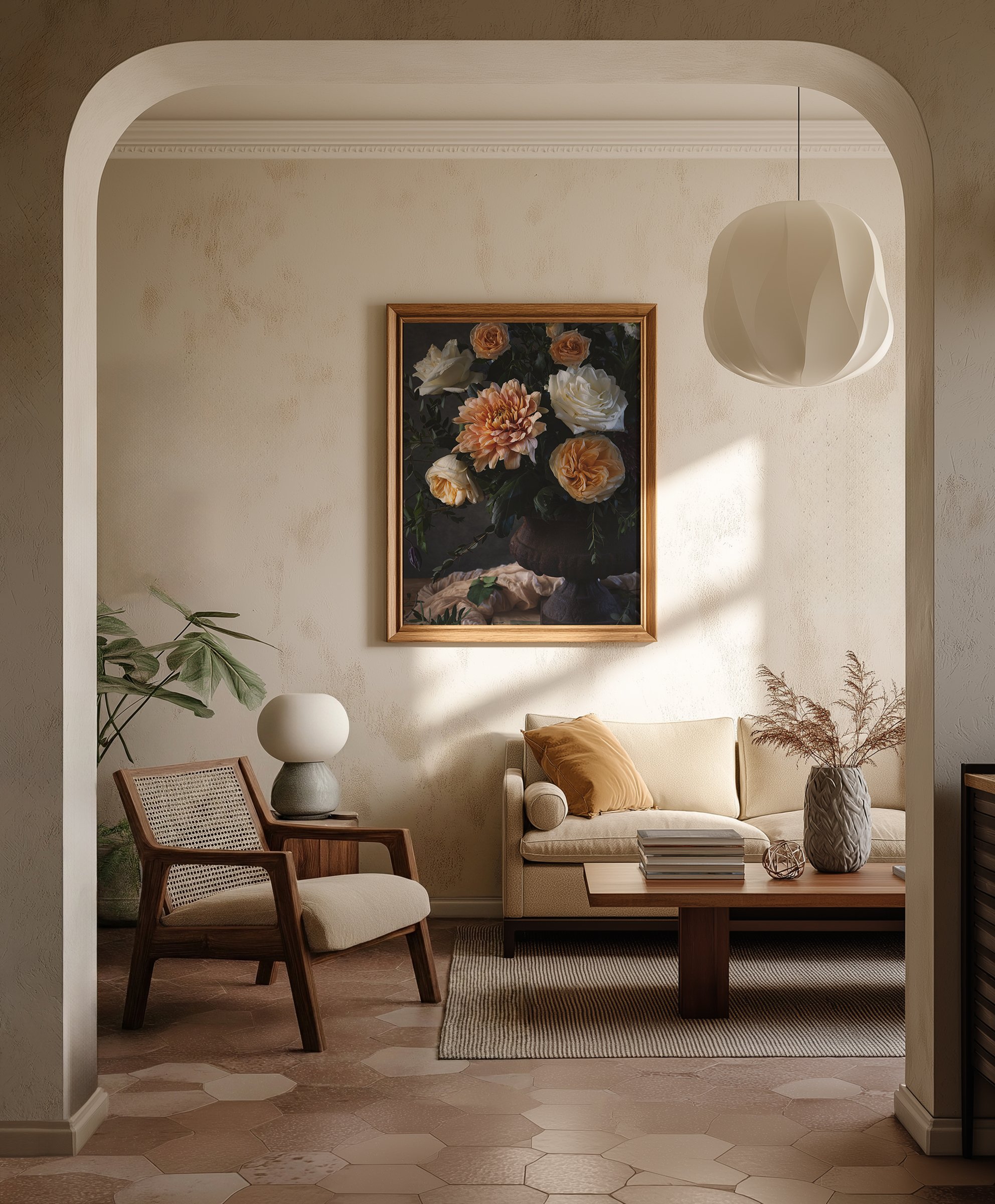 Living room with a beige sofa, a coffee table with books, a patterned vase with dried plants, a framed painting of flowers, a white modern pendant lamp, a table lamp on a side table, and a wooden chair with cane backrest.