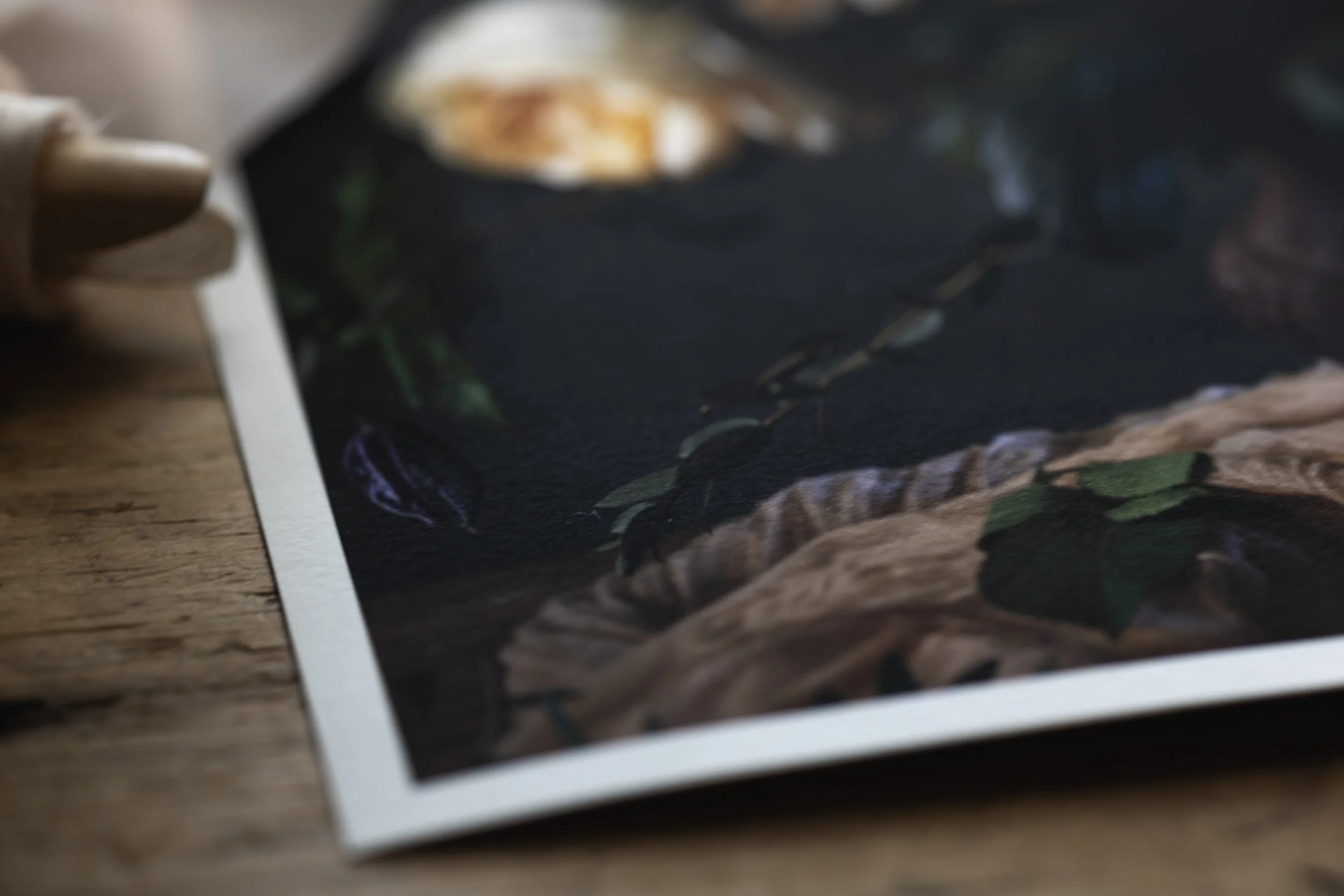 Close-up of a printed photograph placed on a wooden surface, with a blurred edge of the paper visible on the left.