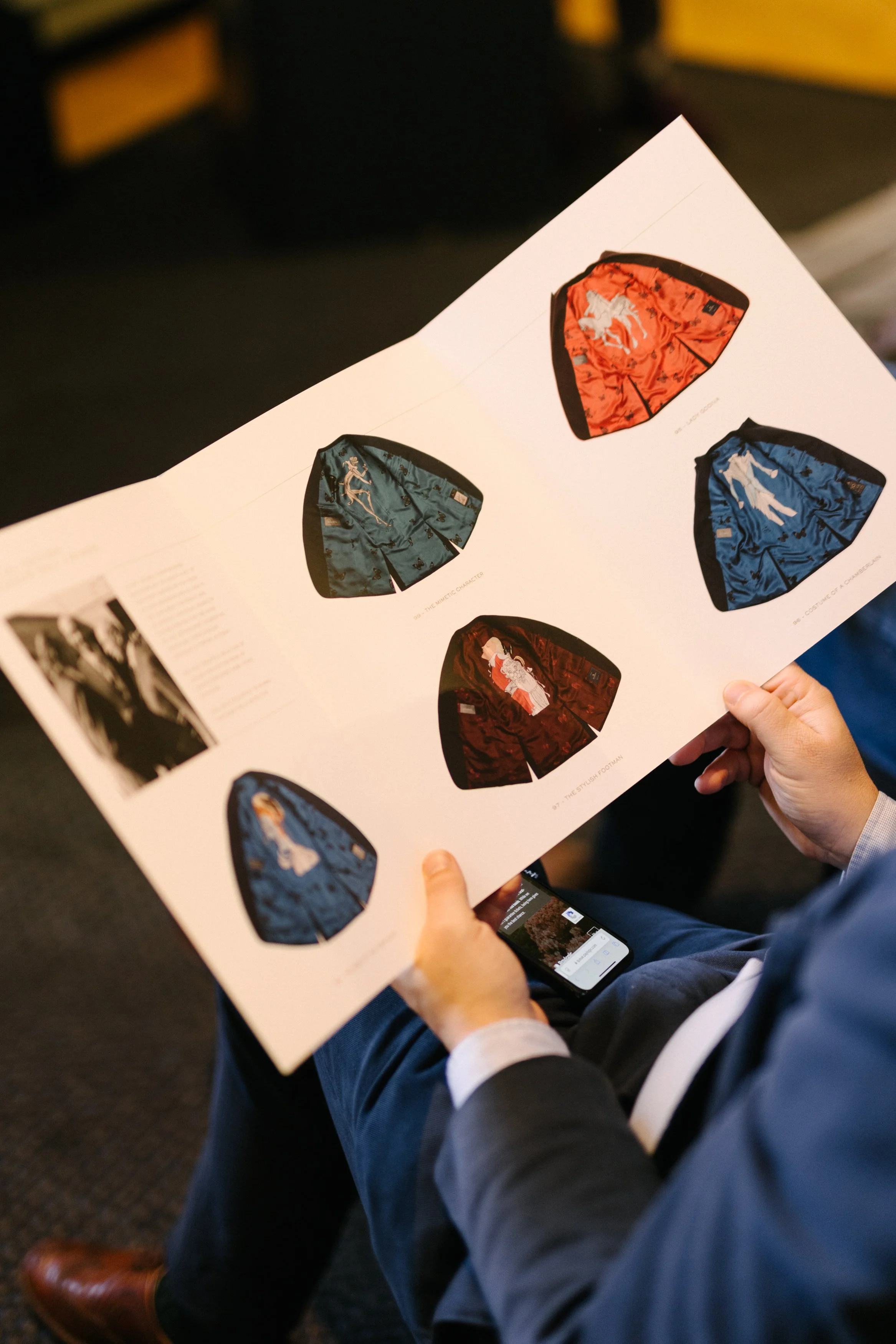 Une personne tient une affiche présentant différentes versions de shorts avec des motifs de personnages tatoués, en bleu, rouge, et marron.