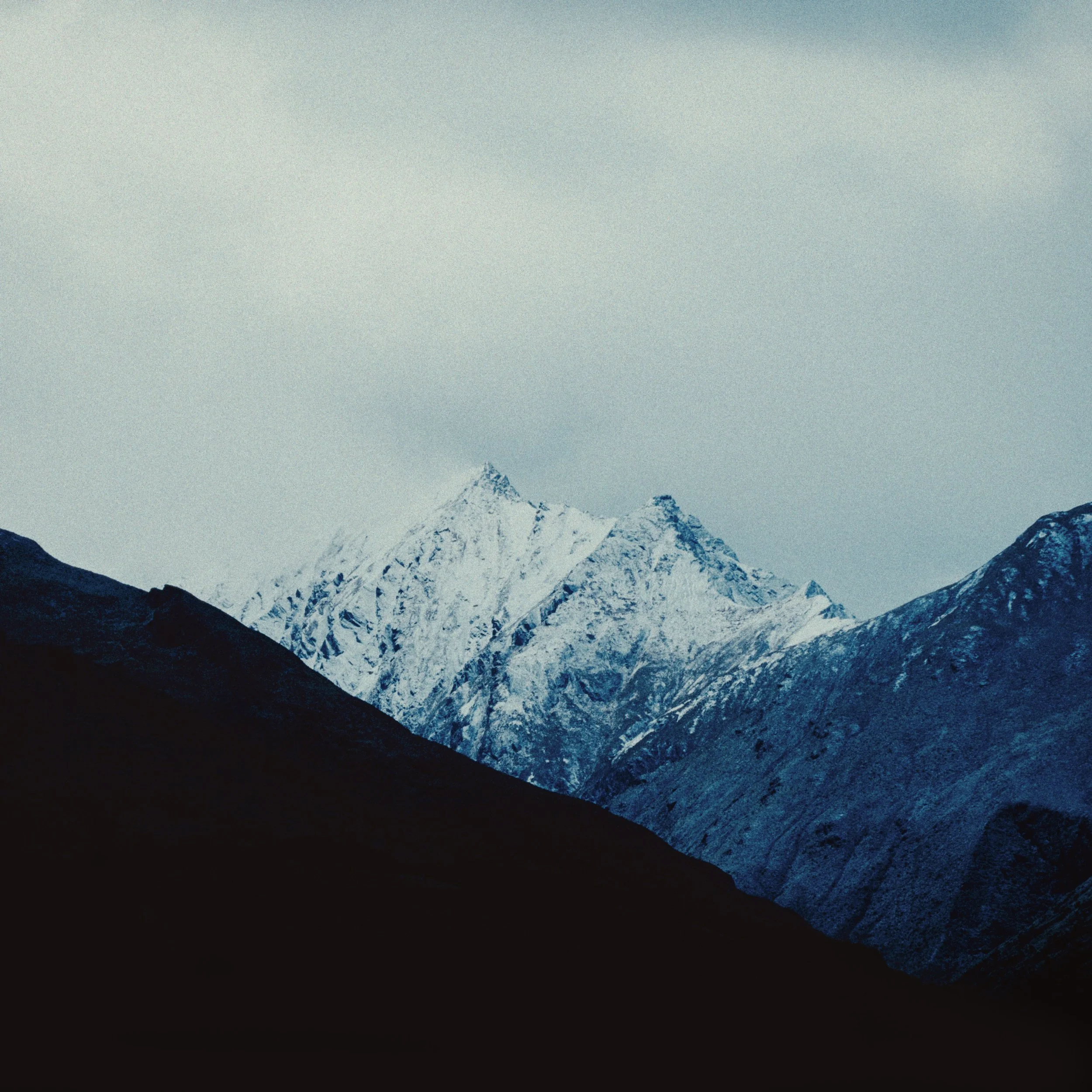 Montagnes enneigées sous un ciel nuageux.