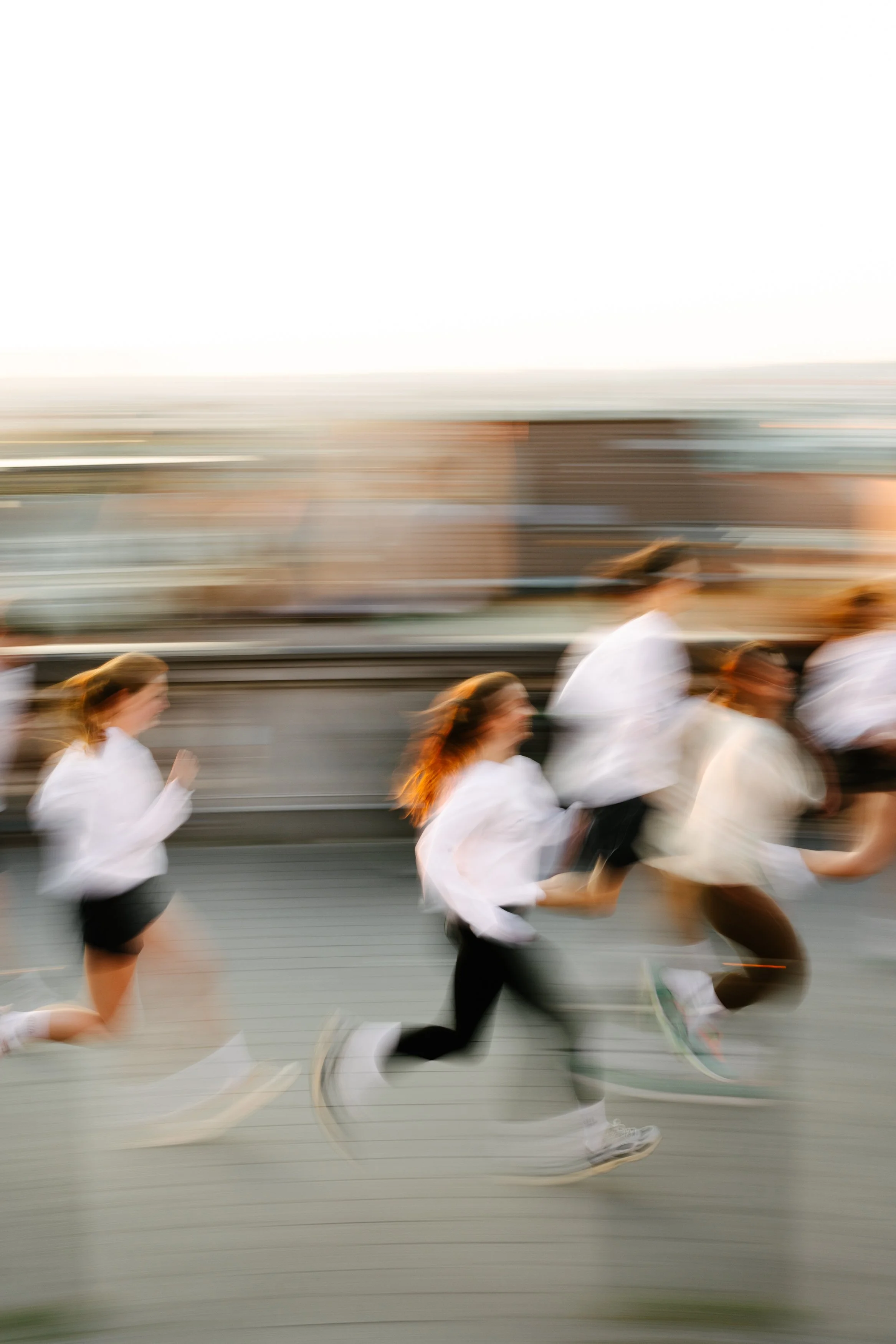 Groupe de personnes courant rapidement sur un pont pendant le coucher du soleil.
