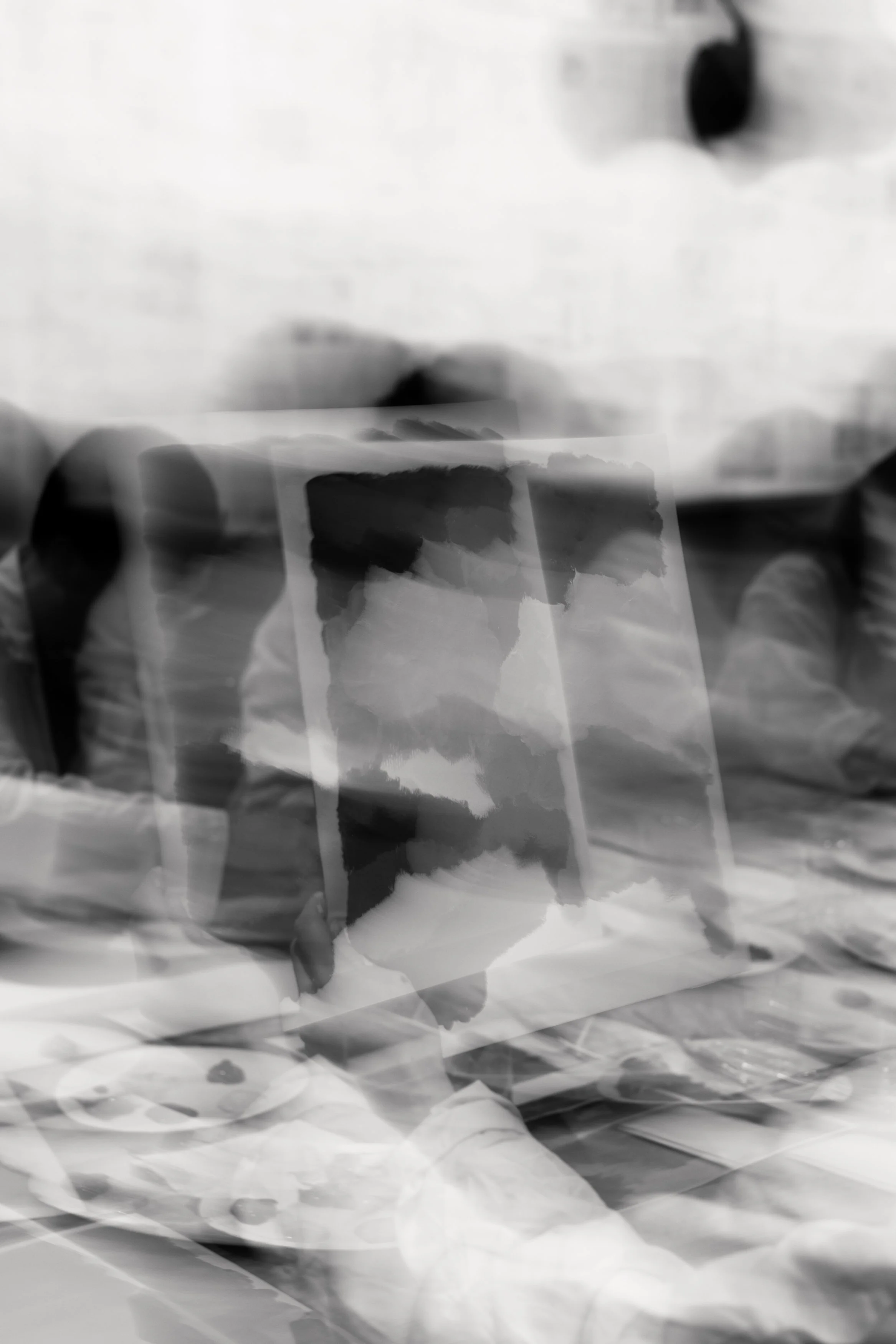 Photo en noir et blanc floue d'une personne tenant une photo ou une peinture lors d'un événement ou d'une exposition.