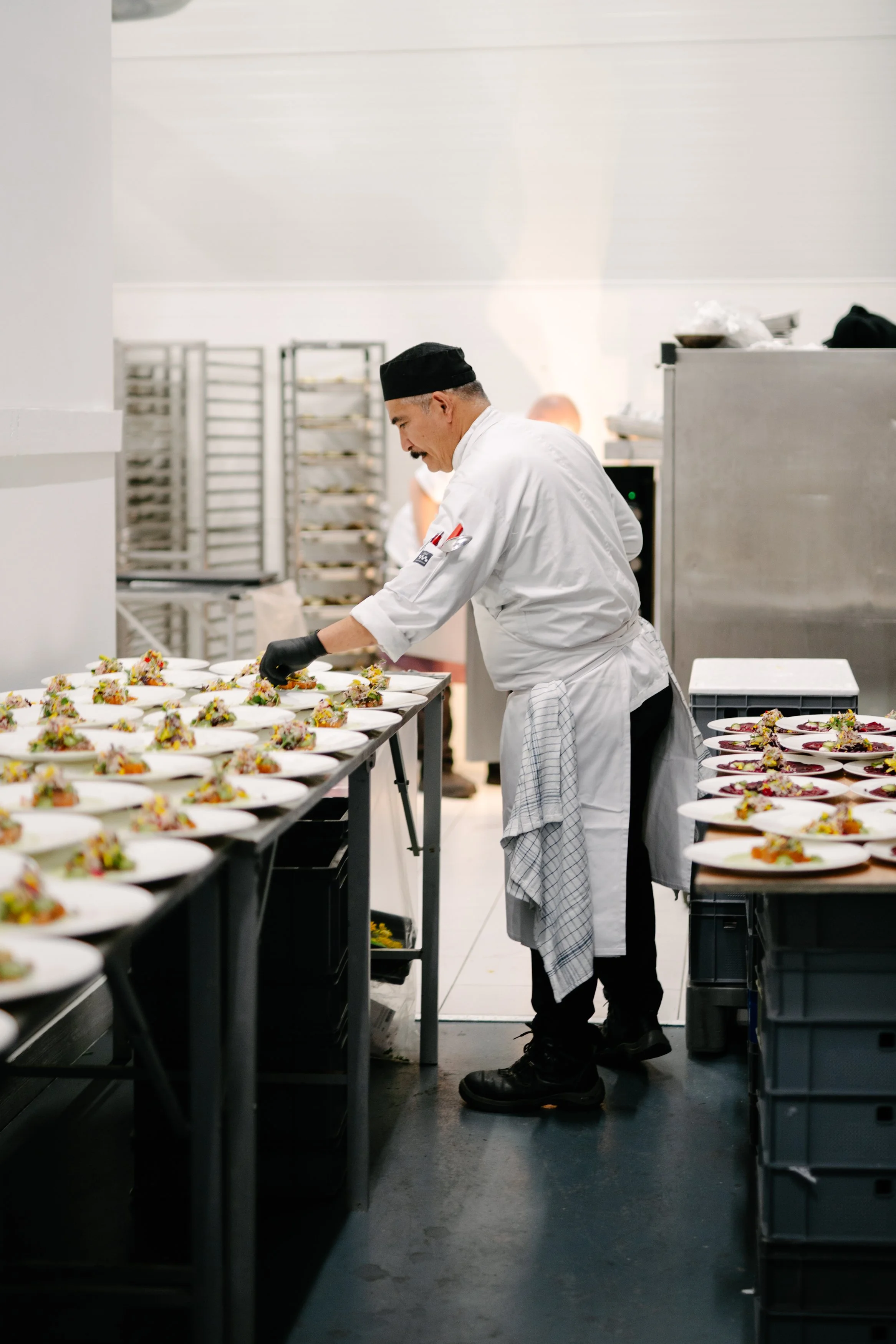 Un chef en uniforme préparant des plats dans une cuisine professionnelle.