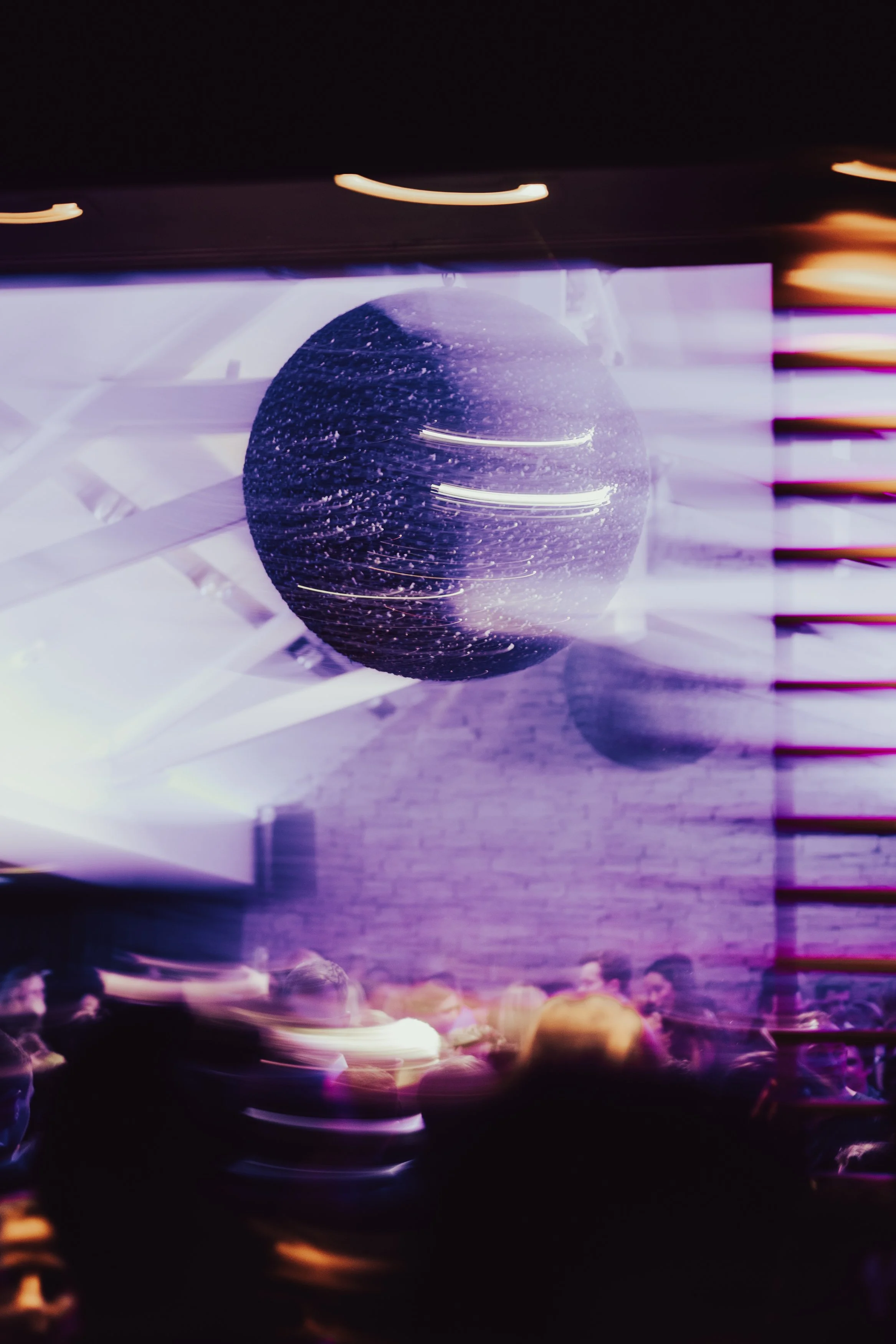 Discobule suspendu dans un lieu lumineux avec ambiance festif, quelqu'un danse en arrière-plan.