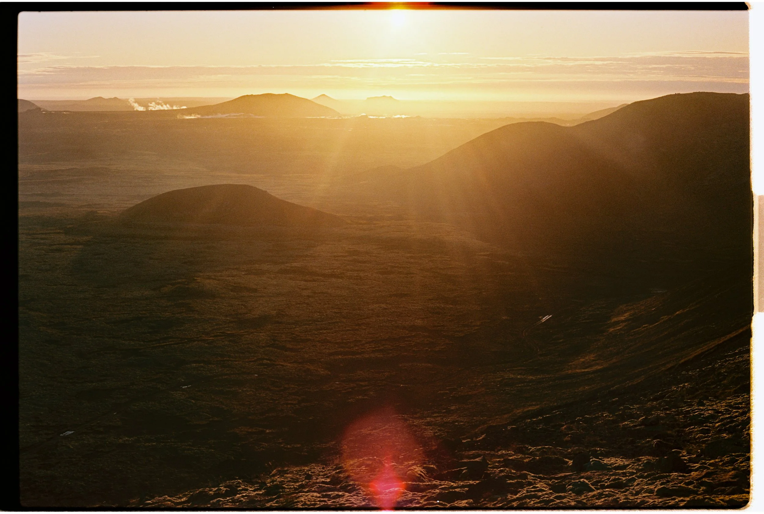 Photo du paysage montagneux au coucher du soleil avec rayons de lumière et des montagnes en arrière-plan.