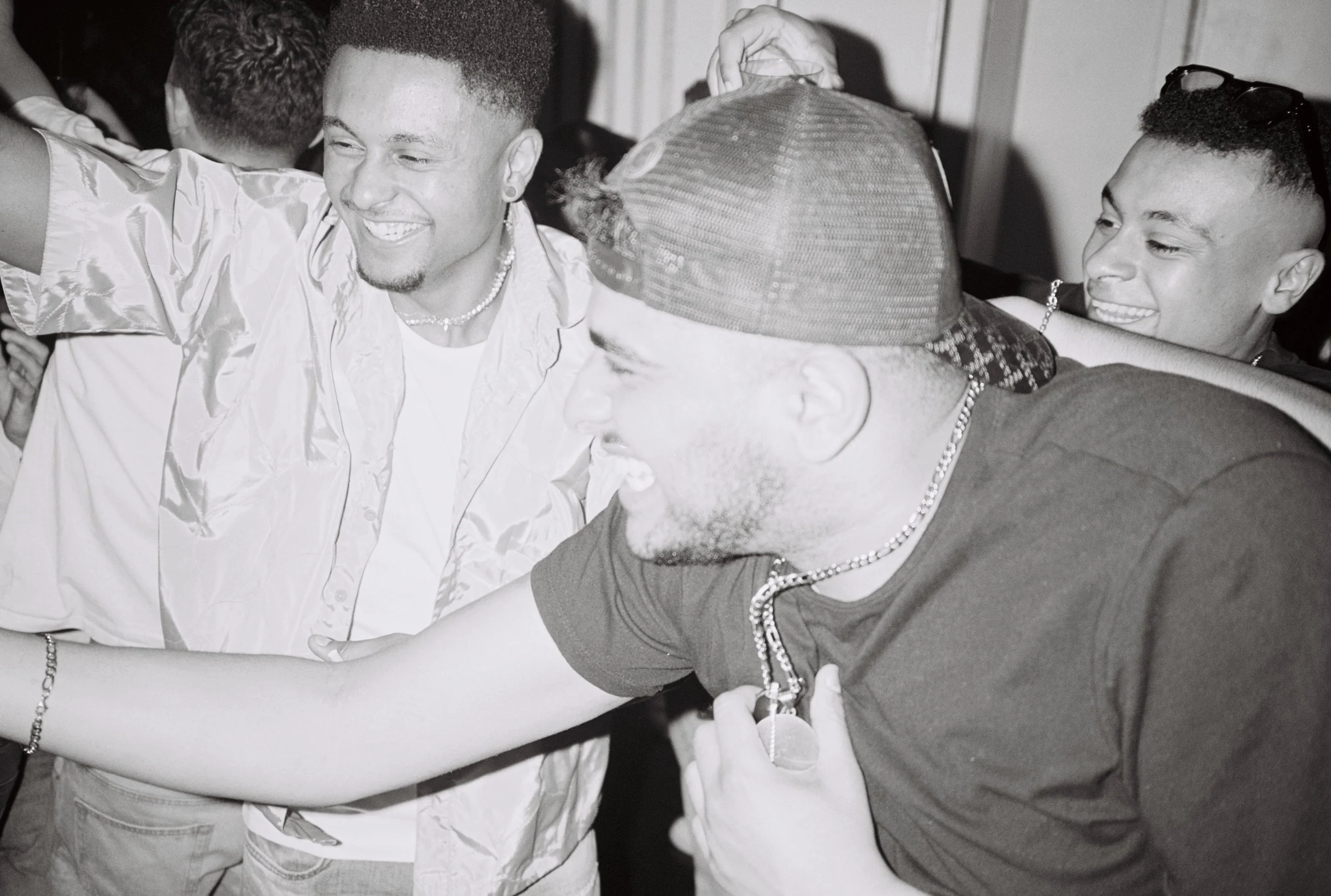 Groupe de jeunes hommes souriants en train de danser et de célébrer, en monochrome