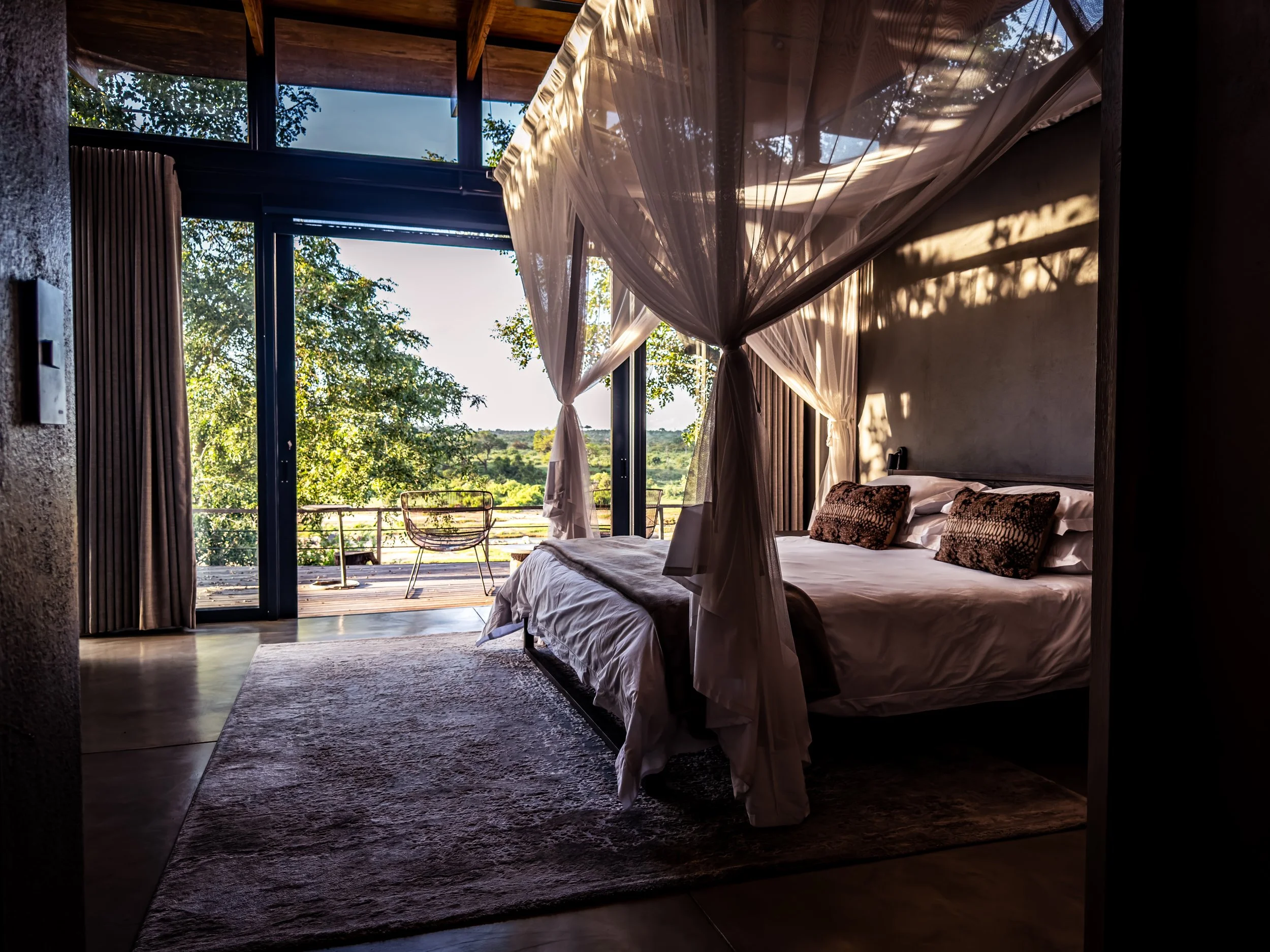 A comfortable safari lodge bedroom with a mosquito net and open views, designed for peaceful nights in the African bush.
