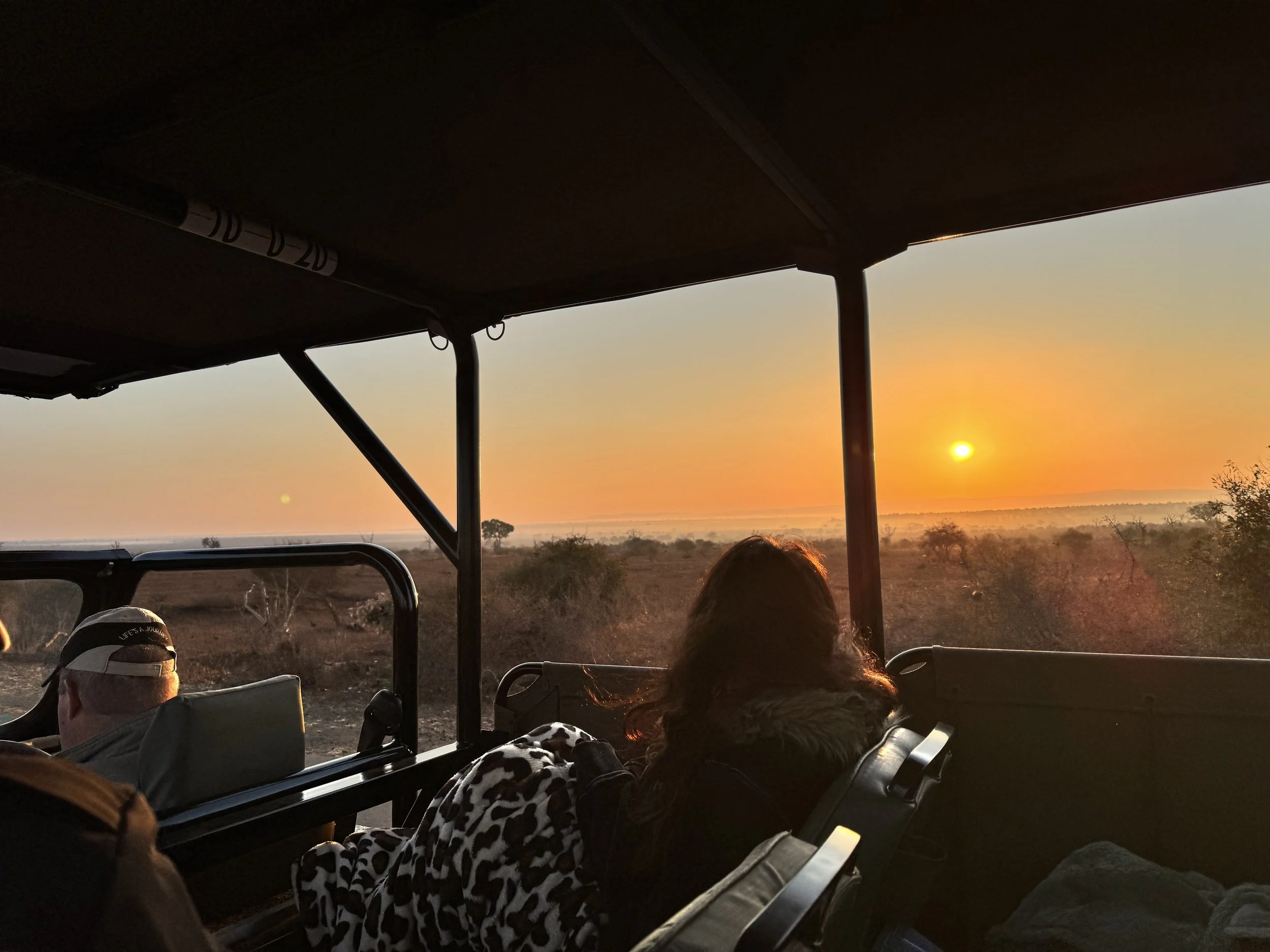 Guests enjoying the sunset on an open game drive.