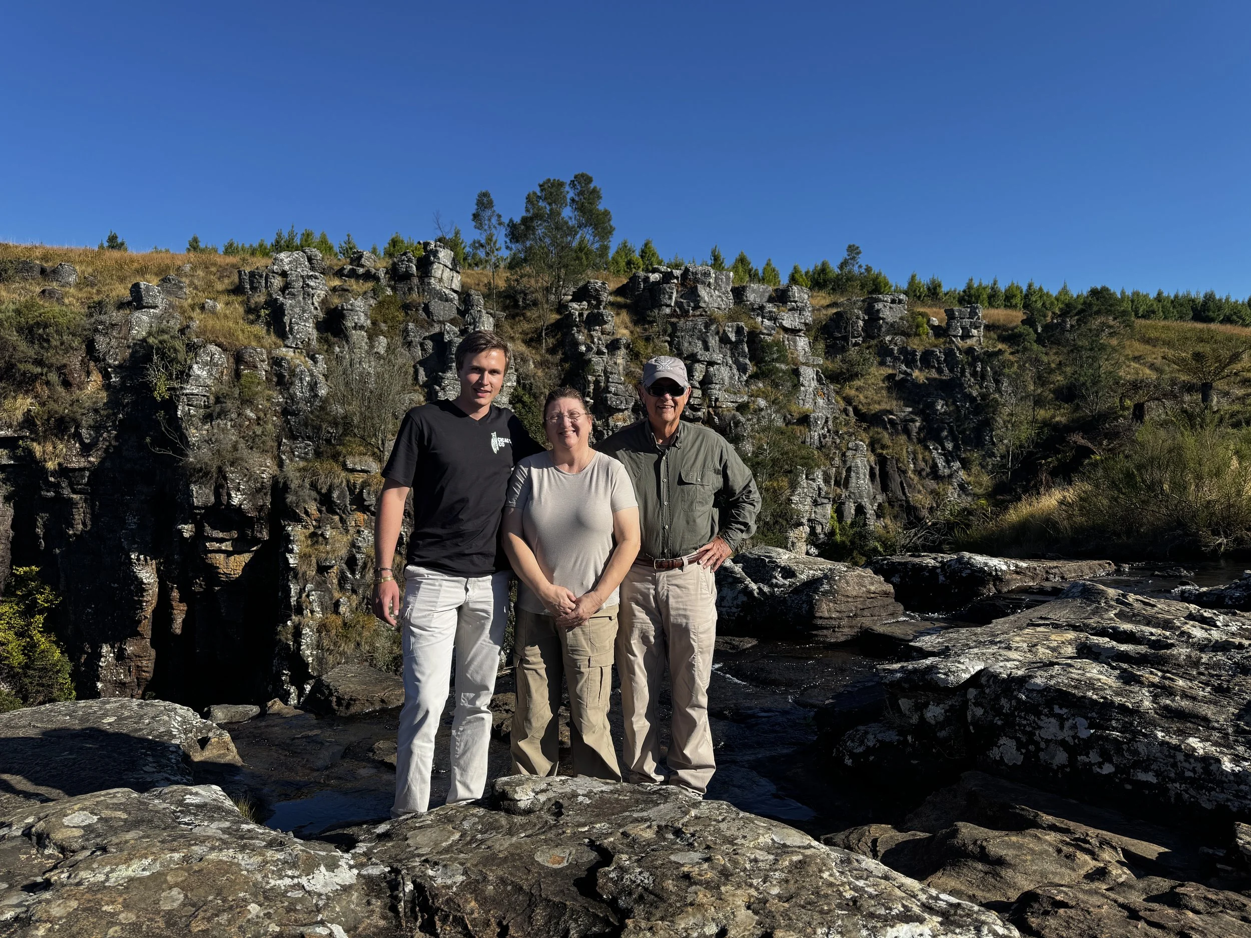 CicadaCo owner Adriaan standing with guests at a waterfall at Pinnacle Rock during a guided scenic excursion.