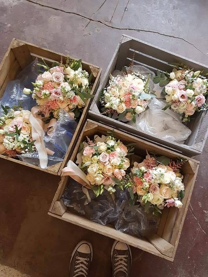 Four wooden crates filled with bouquets of pink and white flowers, ready for a special occasion.