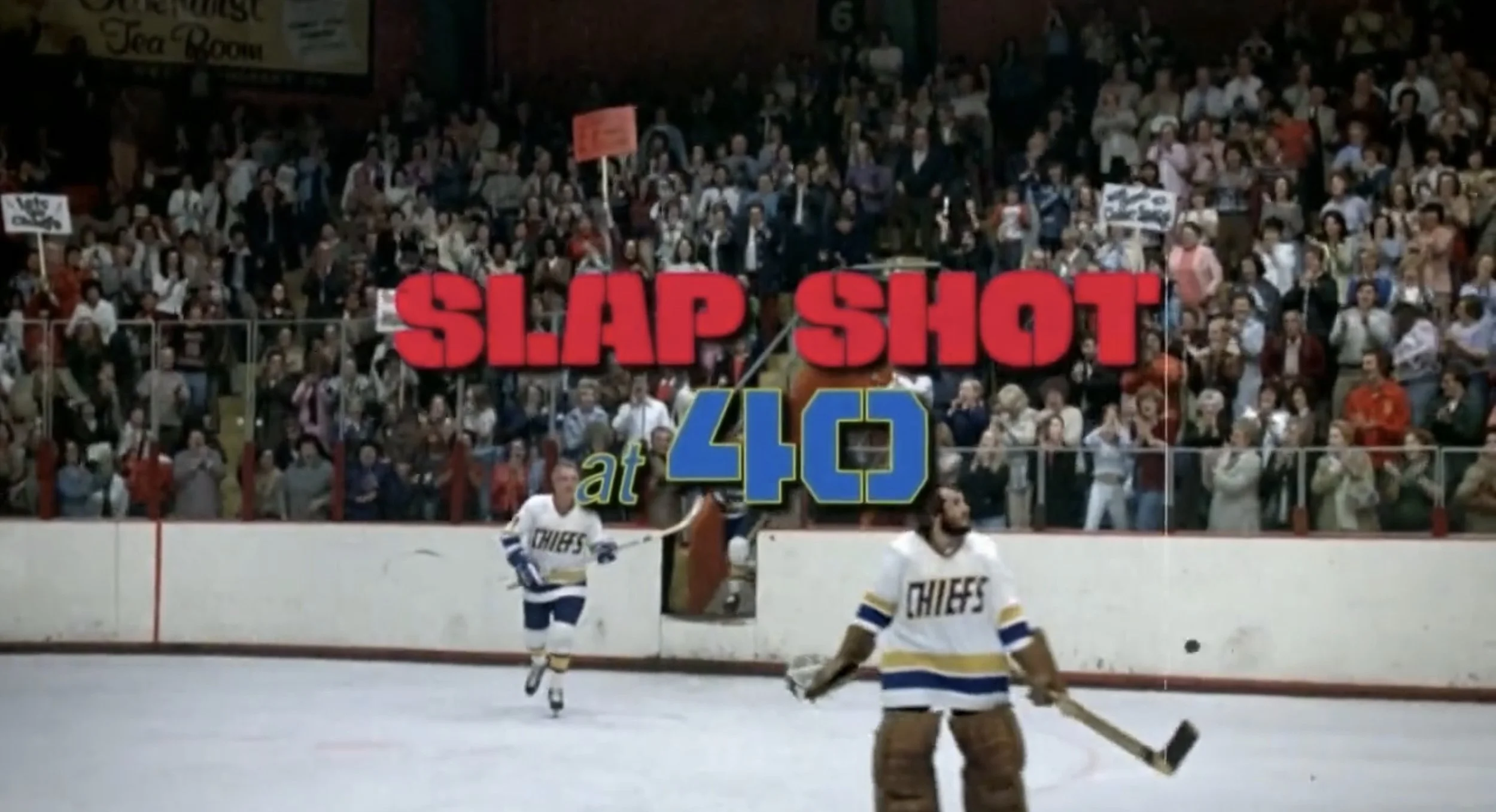 Hockey players in front of a crowd at an ice rink during a game.