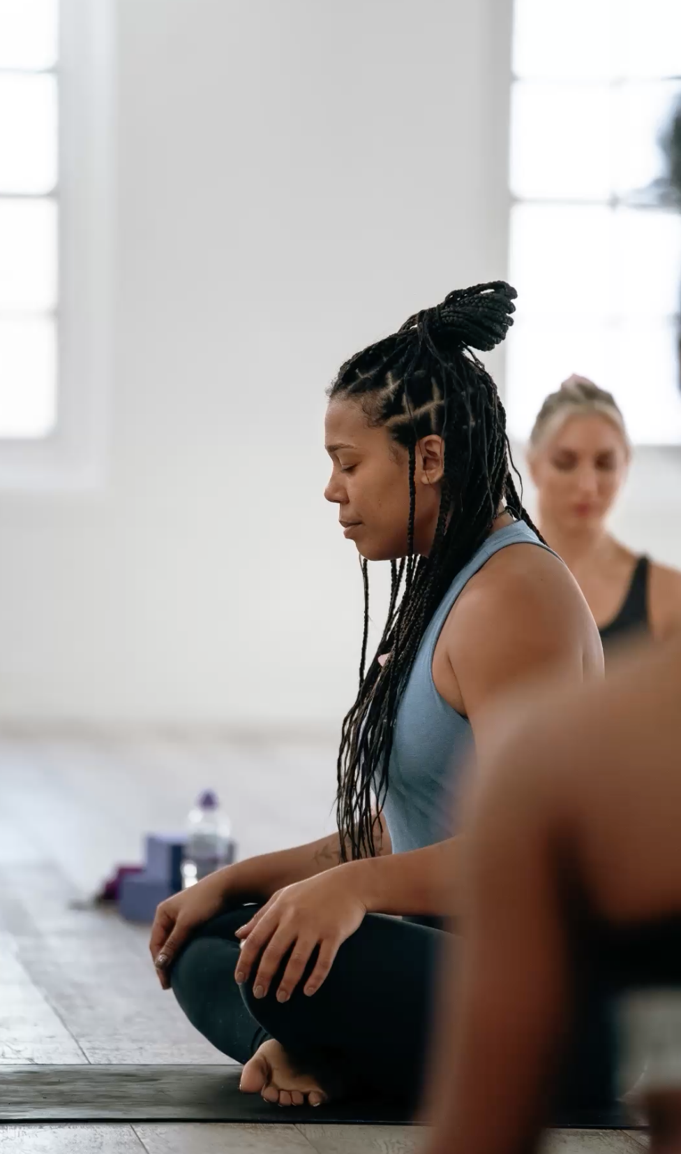 Woman with braided hair meditating in a yoga class.