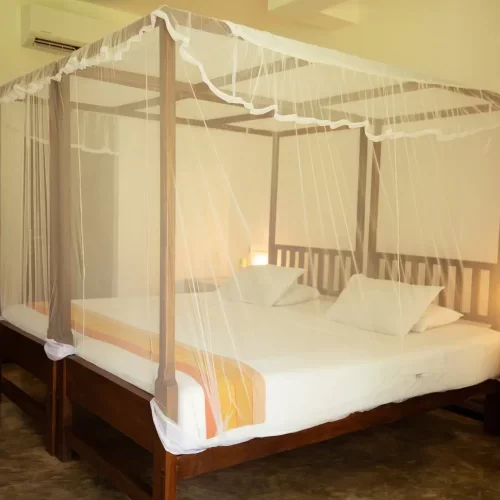A bed with a mosquito net canopy in a hotel room.