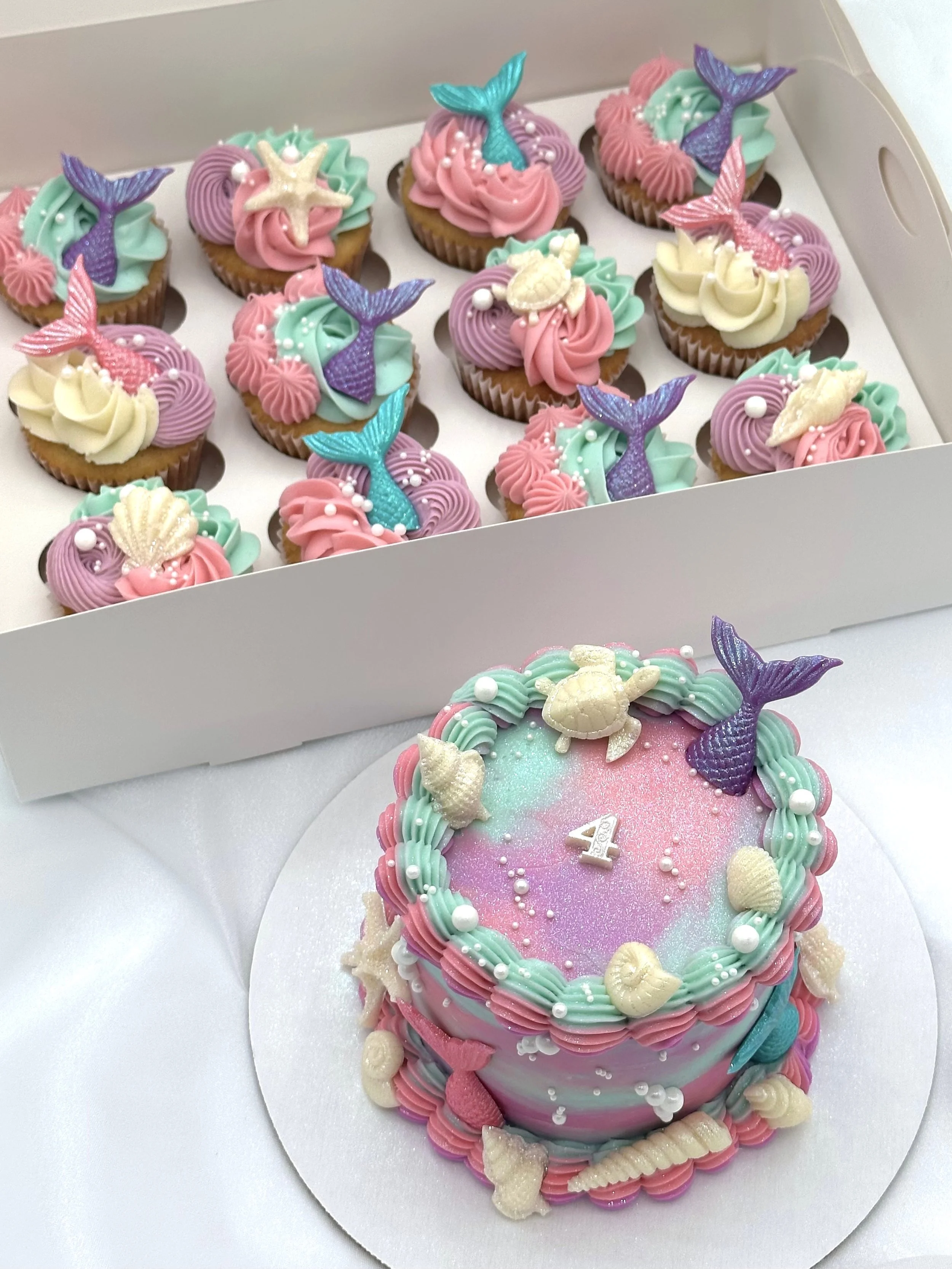Mermaid-themed 4th birthday cake with matching cupcakes decorated with seashells and mermaid tails