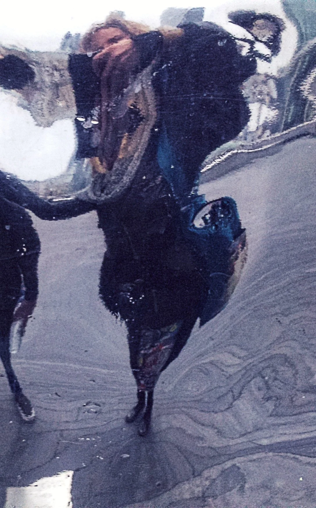 Reflected image of a person taking a photo in a mirror with water or glass creating a distorted effect.