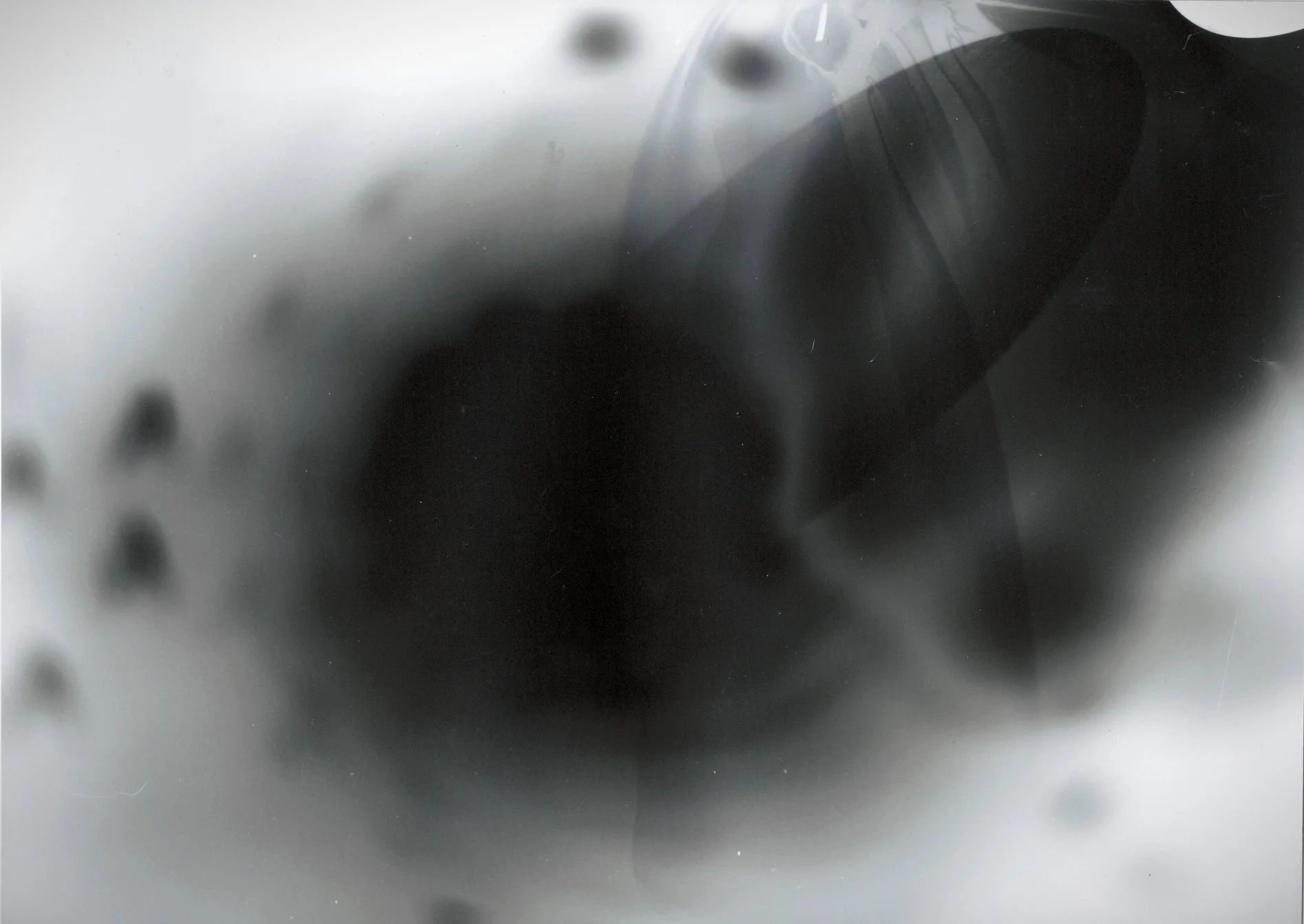 Close-up of a metallic, reflective surface with some blurred black spots and a dark shadow or object.