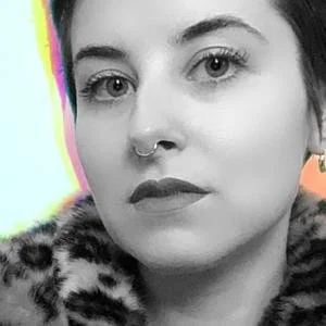 Close-up of a young woman with a septum piercing, wearing dark lipstick and a leopard print coat.