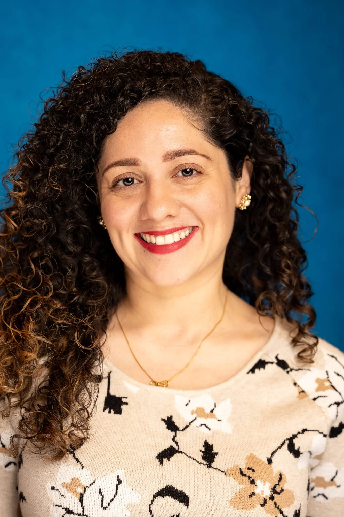 photo of Ilia Perez smiling at camera with blue background
