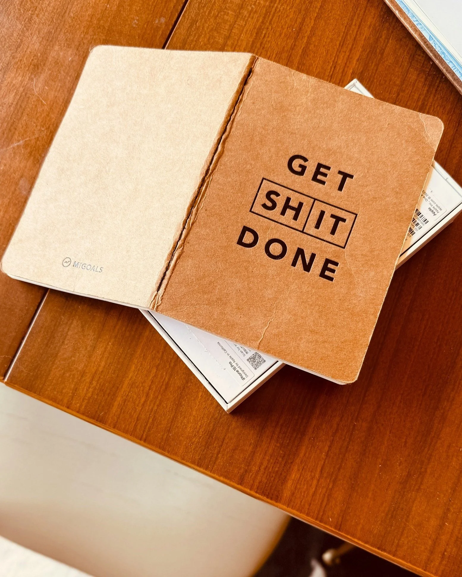 notebook on a wooden table with the title "get sh*t done"