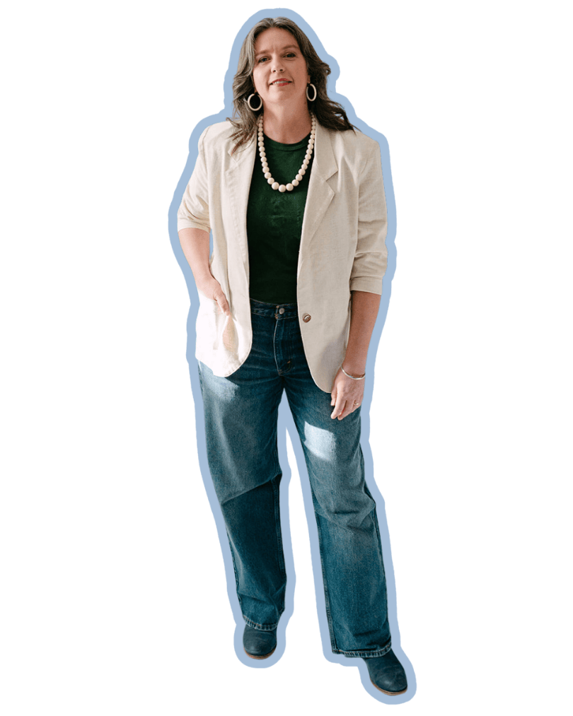 A woman with brown shoulder-length hair, wearing a beige blazer, green shirt, a pearl necklace, and bracelets, smiling