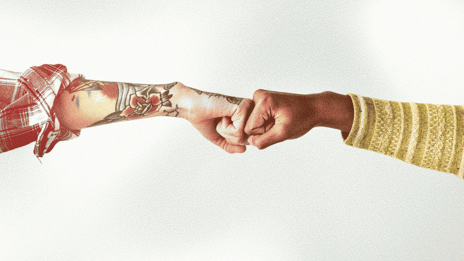 two people pump fists in agreement, one with vibrant arm tattoos, one with a yellow striped sweater, just their arms and fists showing