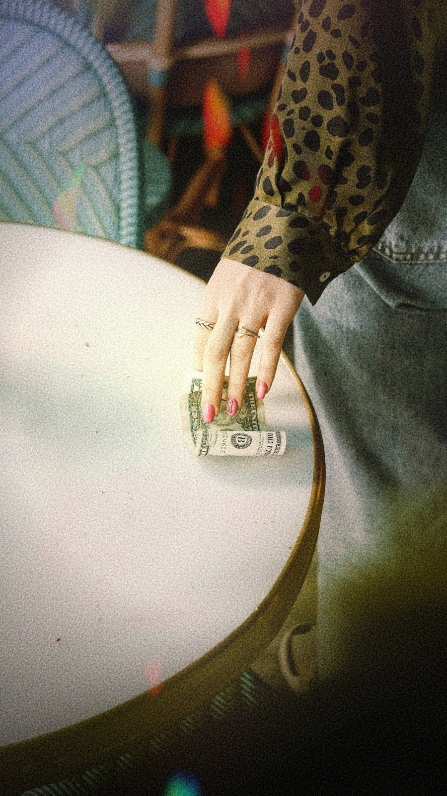 Woman picking up a dollar bill from a table
