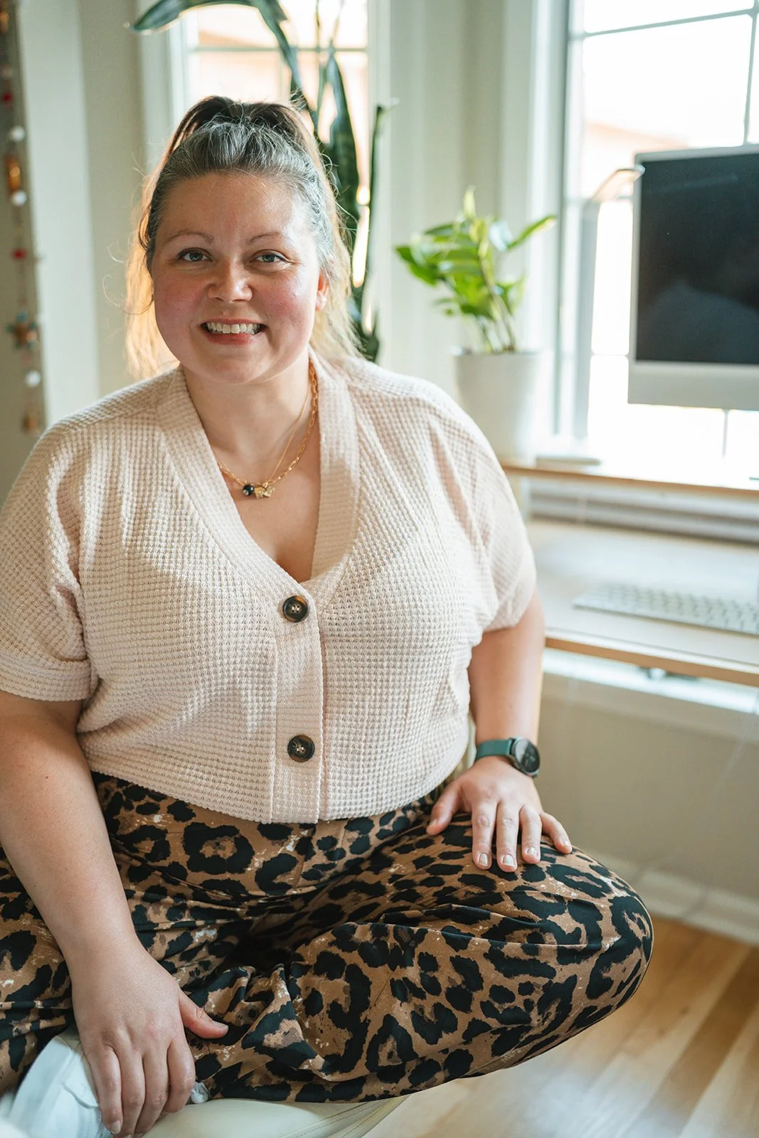 Woman sits at a desk and smiles at the camera