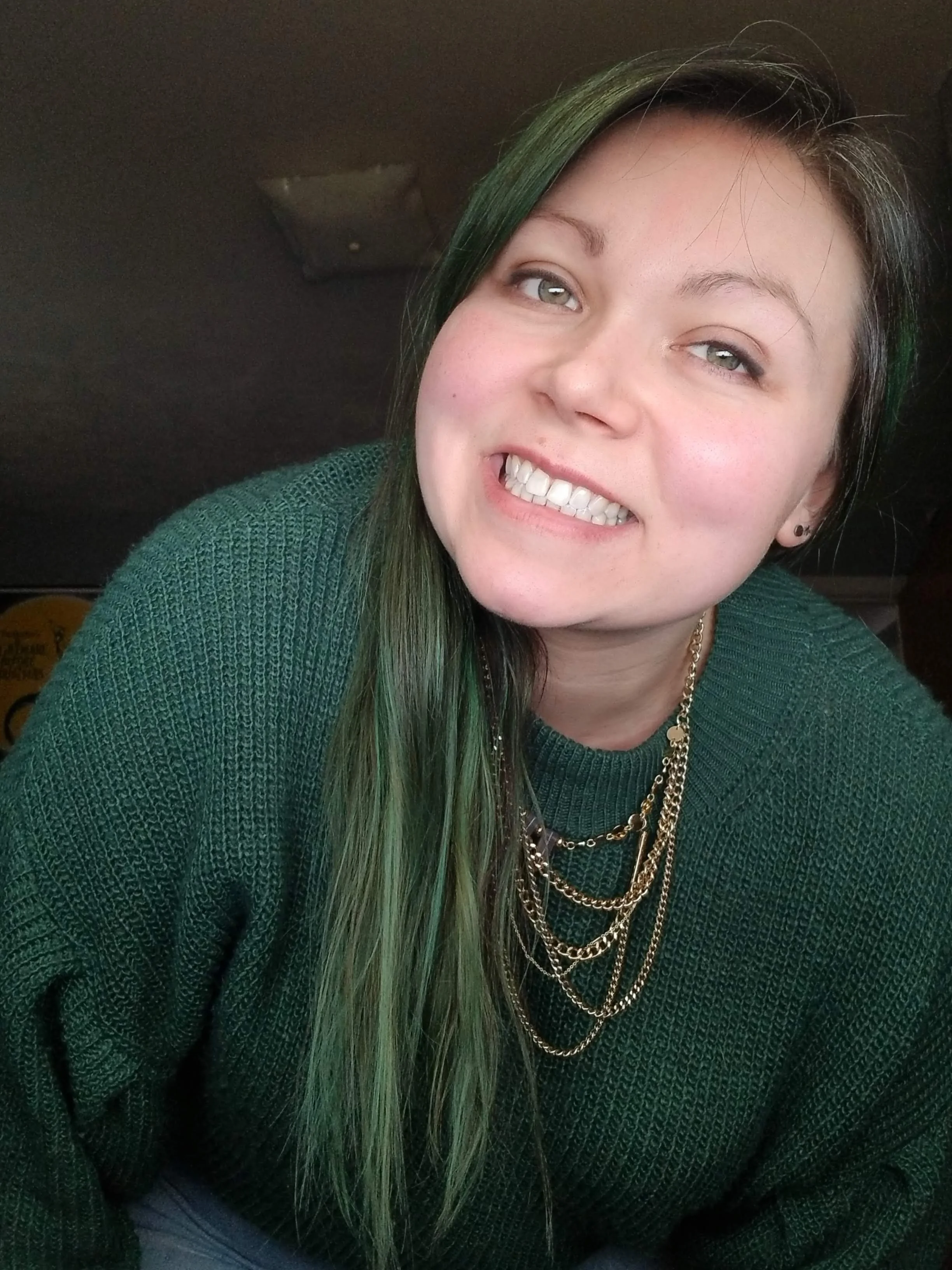 Woman with long green hair smiles at camera