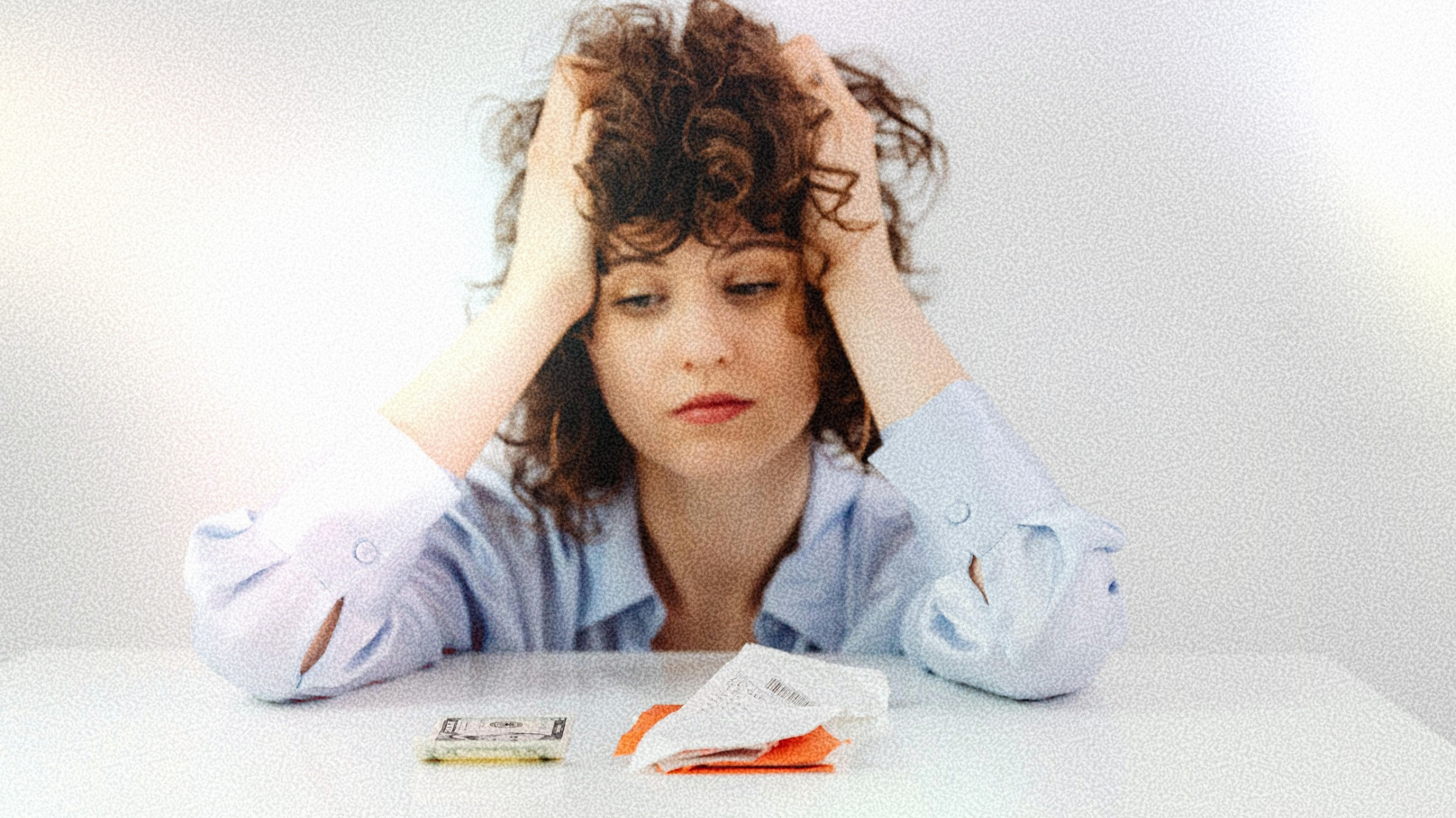 woman with brown curly hair looking at money and receipts, hands on head stressed