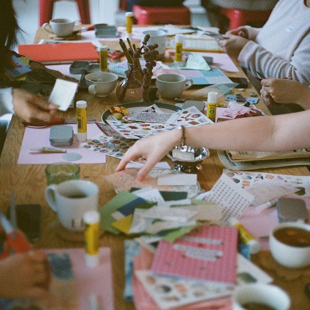 a group of women are crafting at a table with various art supplies