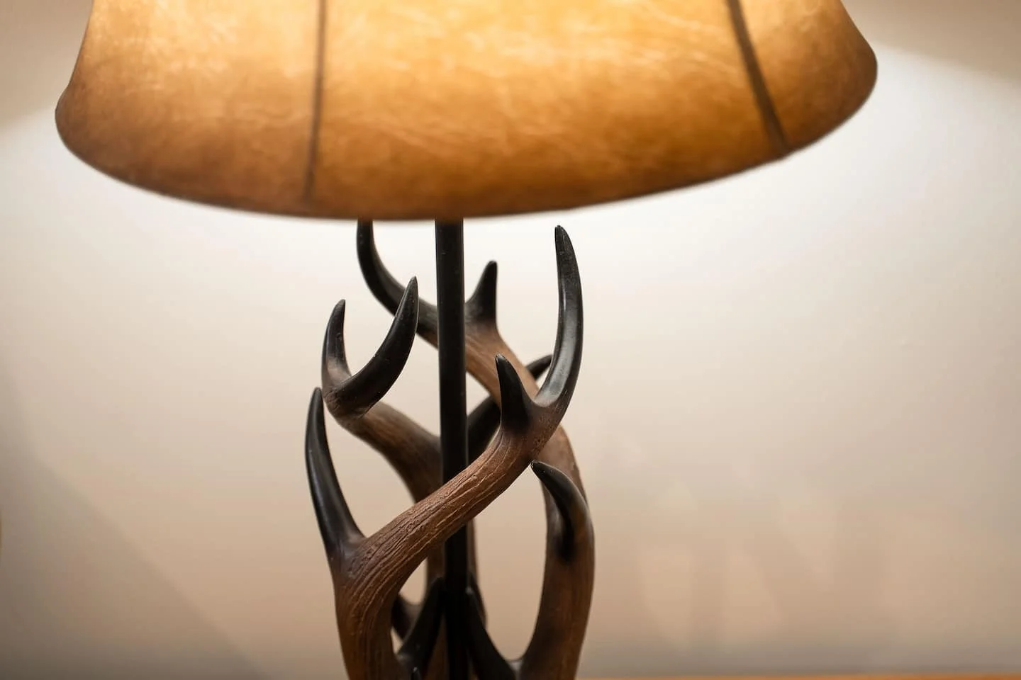 A decorative table lamp featuring a base made of intertwined antlers, topped with a brown lampshade.