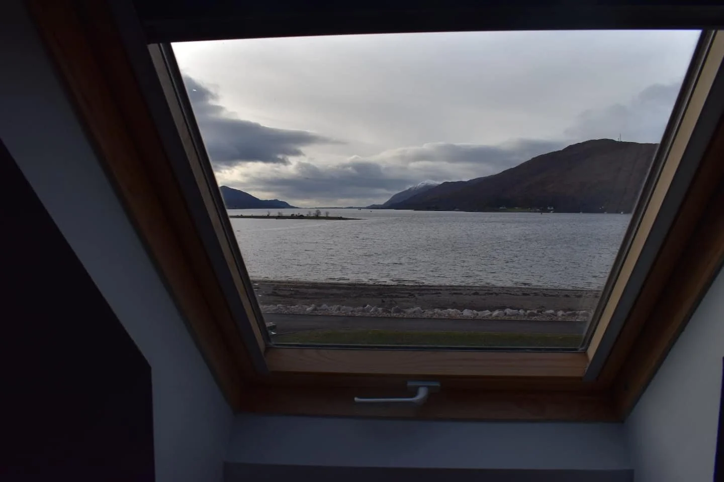 View of a lake with mountains in the distance through a window skylight.