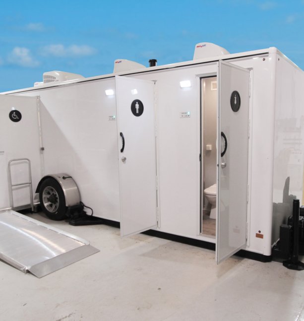Portable restroom trailers with individual compartments, includes accessible restroom, in an outdoor area.