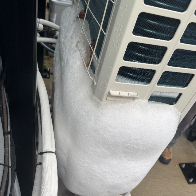 Large block of expanded foam insulation around an air conditioning unit, with wires and pipes nearby.