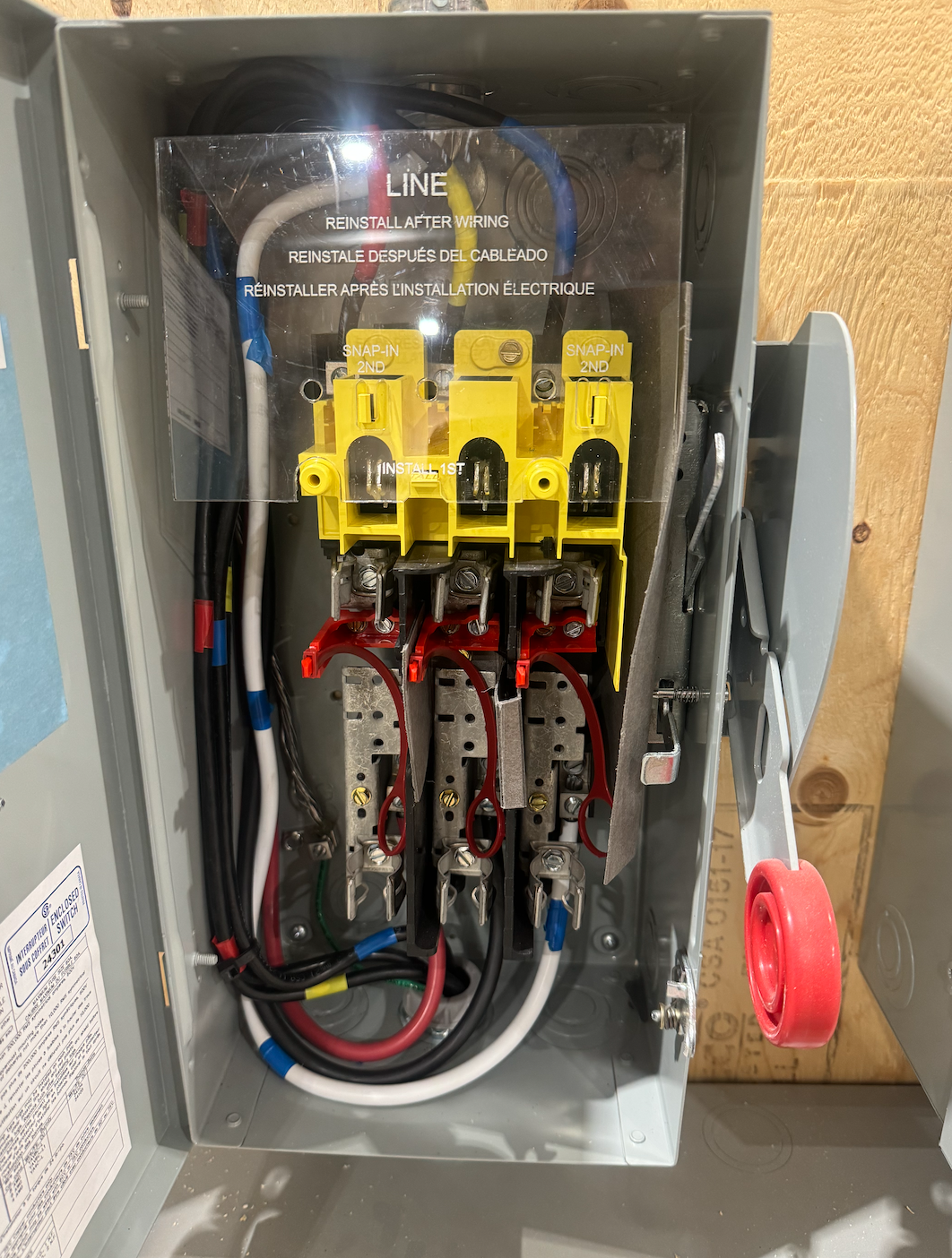 Electrical panel with wiring, circuit breakers, and labels indicating 'Reinstall after wiring' and 'Install first'.
