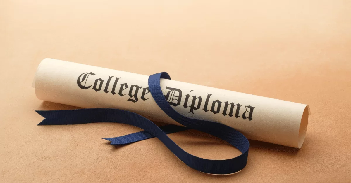 Rolled-up college diploma with a blue ribbon on a beige surface.