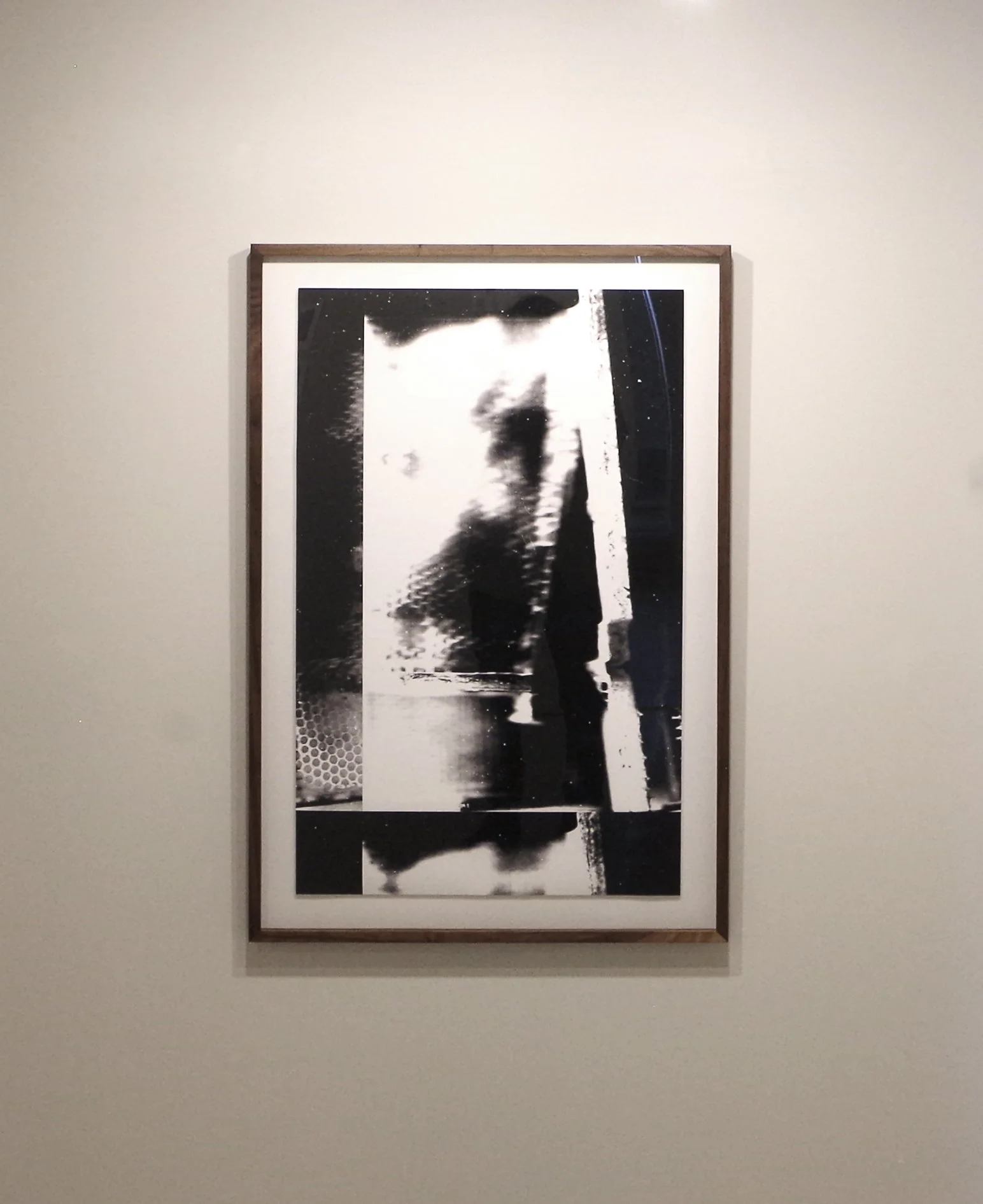 Une œuvre d'art abstraite en noir et blanc encadrée, accrochée sur un mur blanc.