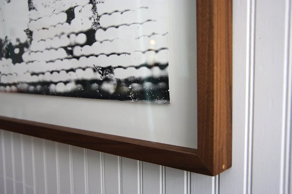 Photo d'une fenêtre avec des gouttes d'eau sur le verre, encadrée en bois, dans une pièce avec un mur en lambris blanc.