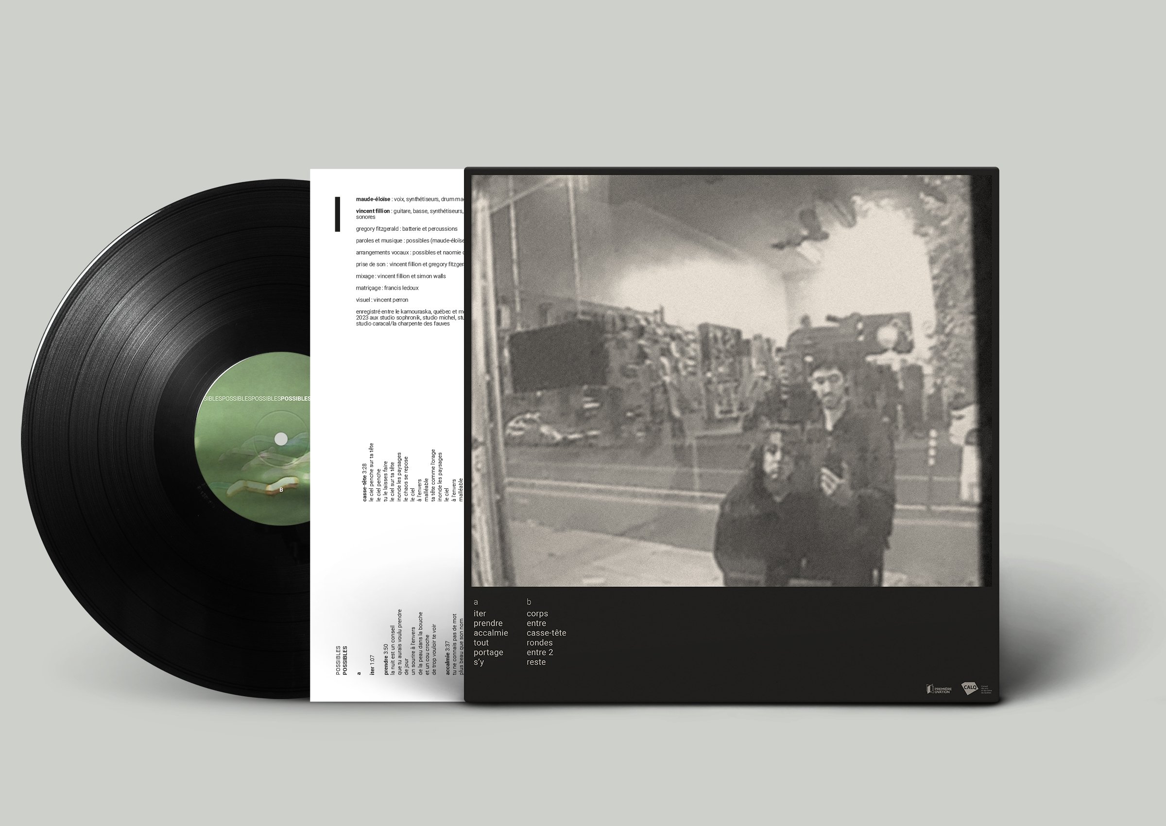 Une photographie en noir et blanc de deux jeunes hommes, l'un debout et l'autre assis, pris à travers une vitre, avec une ville et des véhicules en arrière-plan.