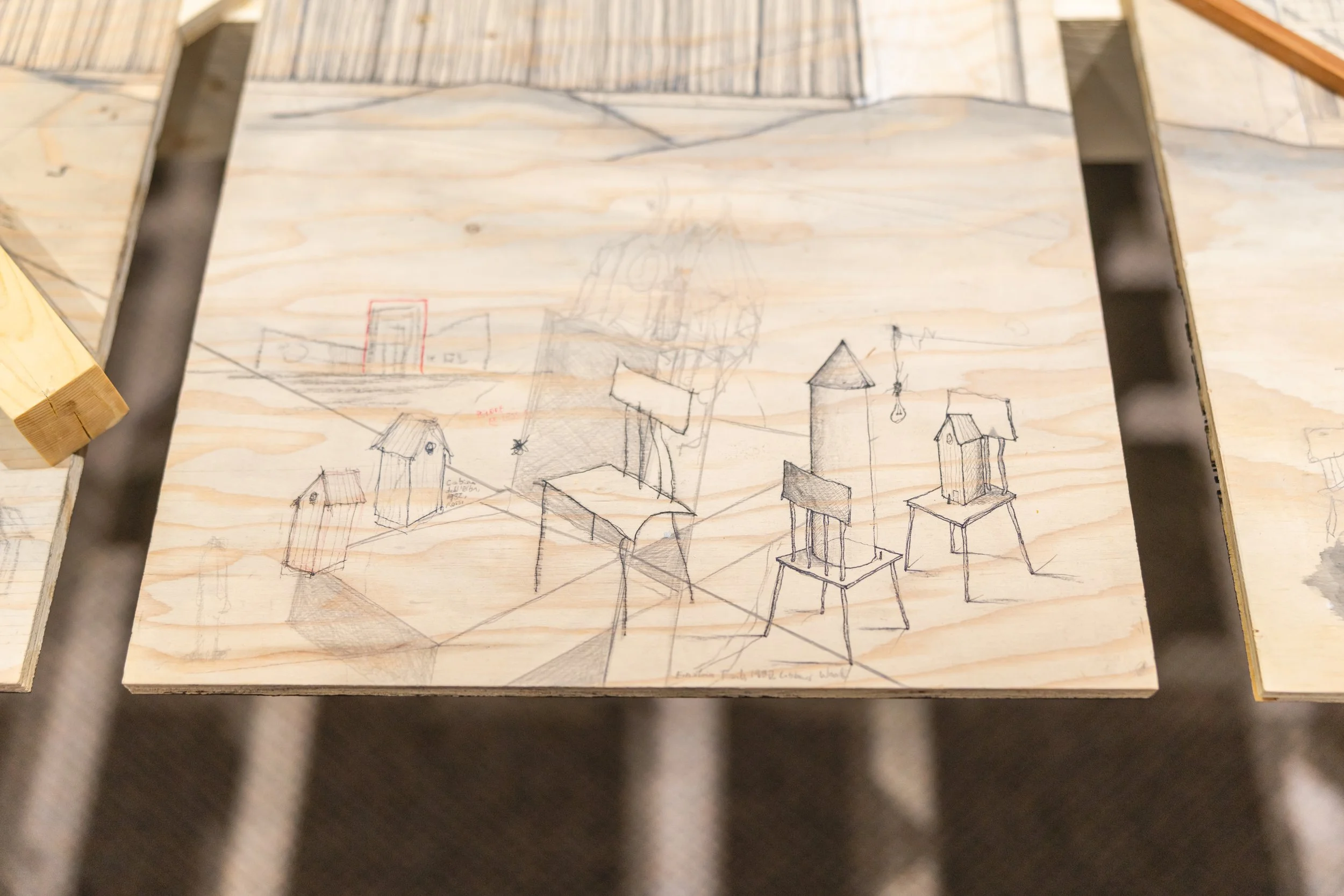 Dessin de croquis de plusieurs petites maisons sur une planche de bois.