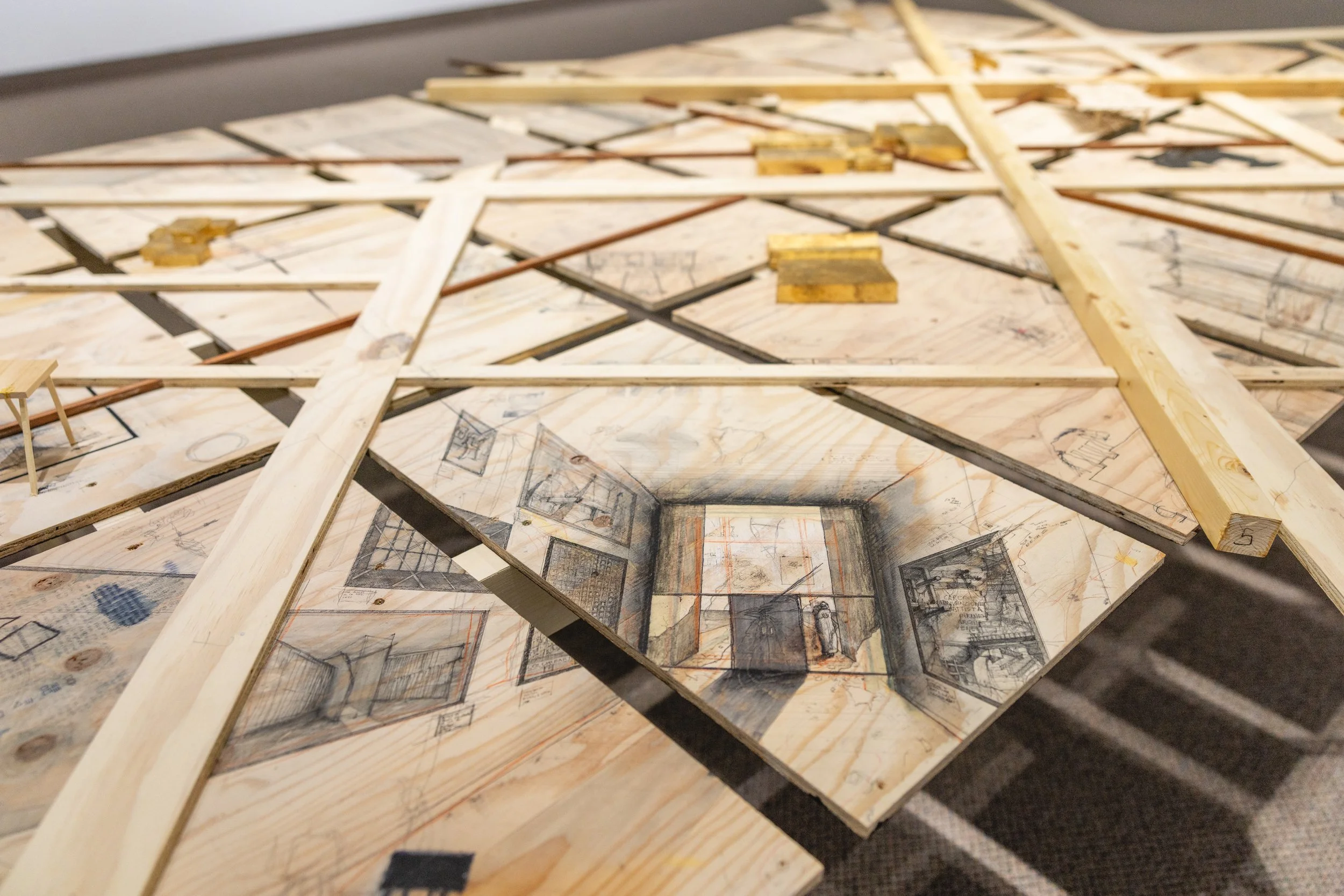 Maquette architecturale faite de planches en bois avec des dessins de plans et intérieurs d'une pièce, composée de croquis et d'outils de construction.