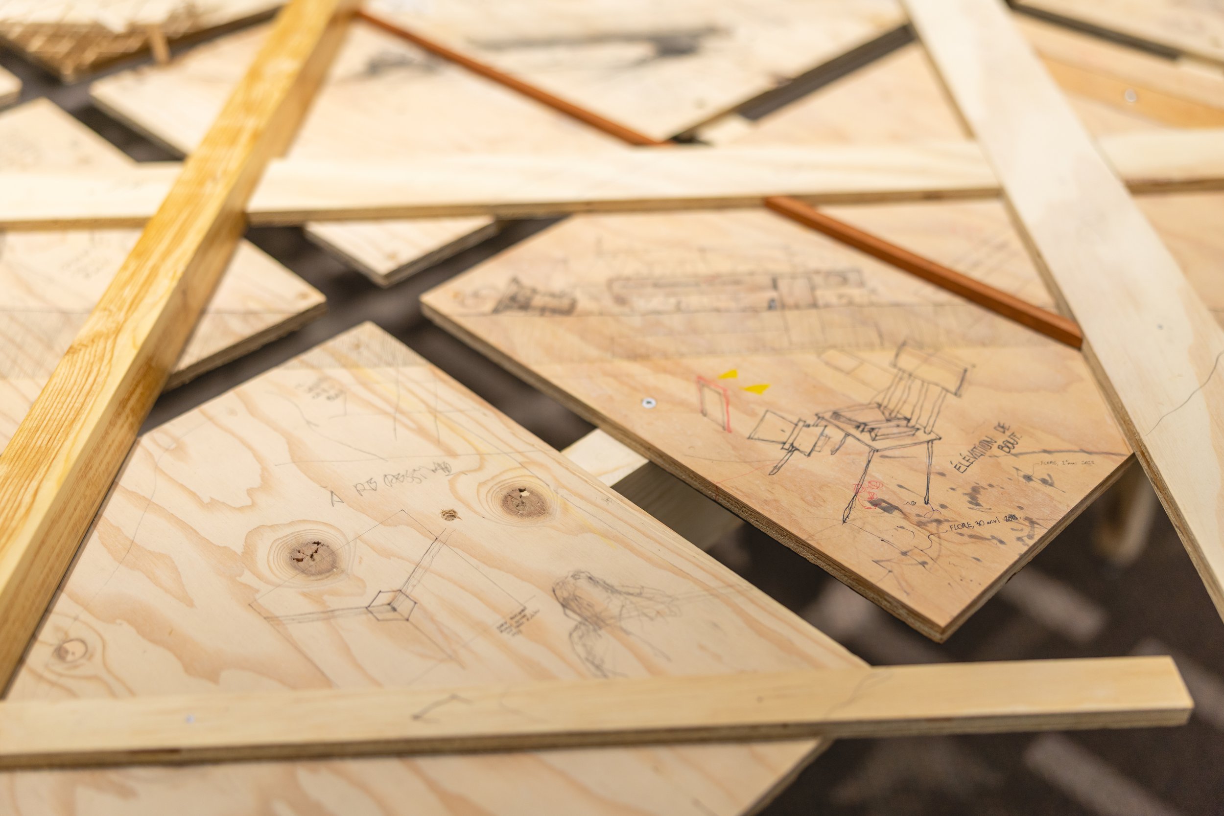 Dessins techniques et esquisses de meubles sur des planches de bois, avec quelques lignes et notes, utilisées pour la conception de meubles ou d'objets.